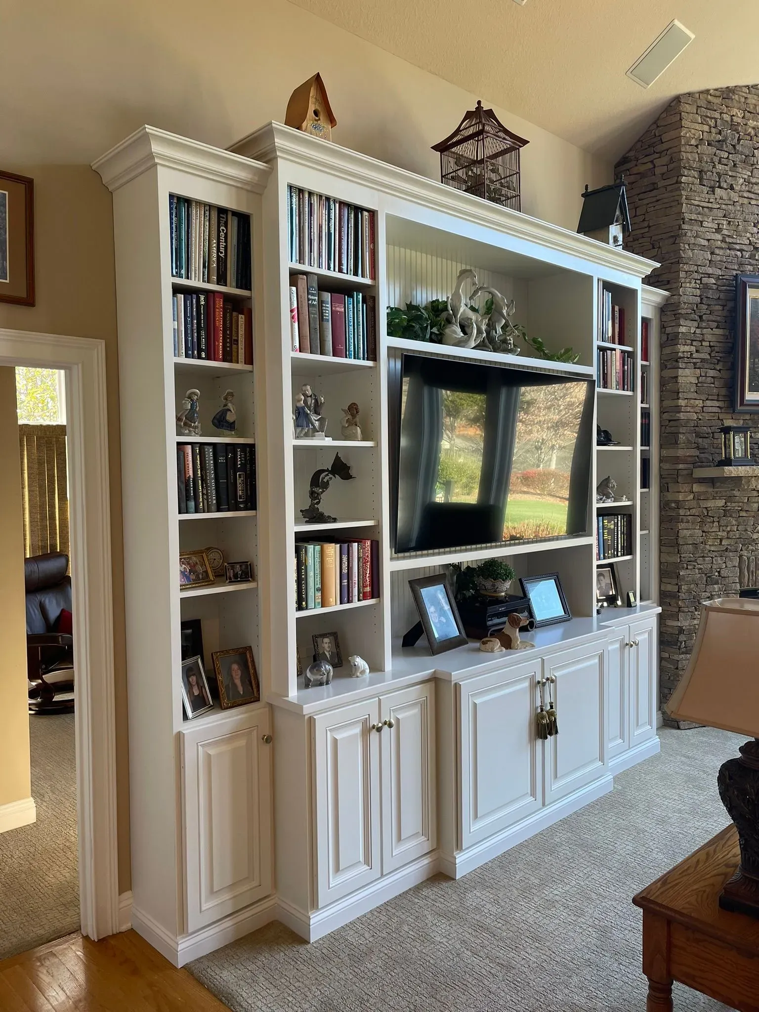 White built-in living room entertainment center with bookshelves, TV, and decorative items