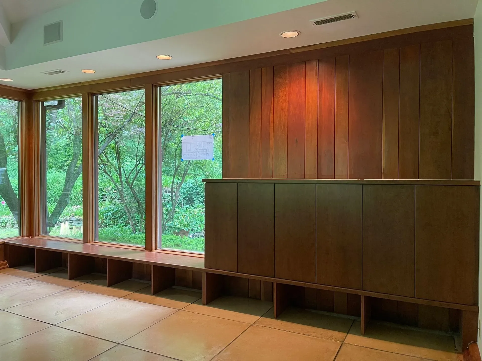 Empty modern waiting room with wood-paneled wall, large windows, and built-in benches.