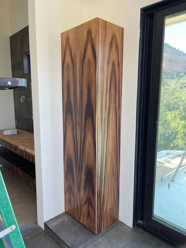 Wood-paneled corner cabinet beside a glass door in a bright room with mountain views