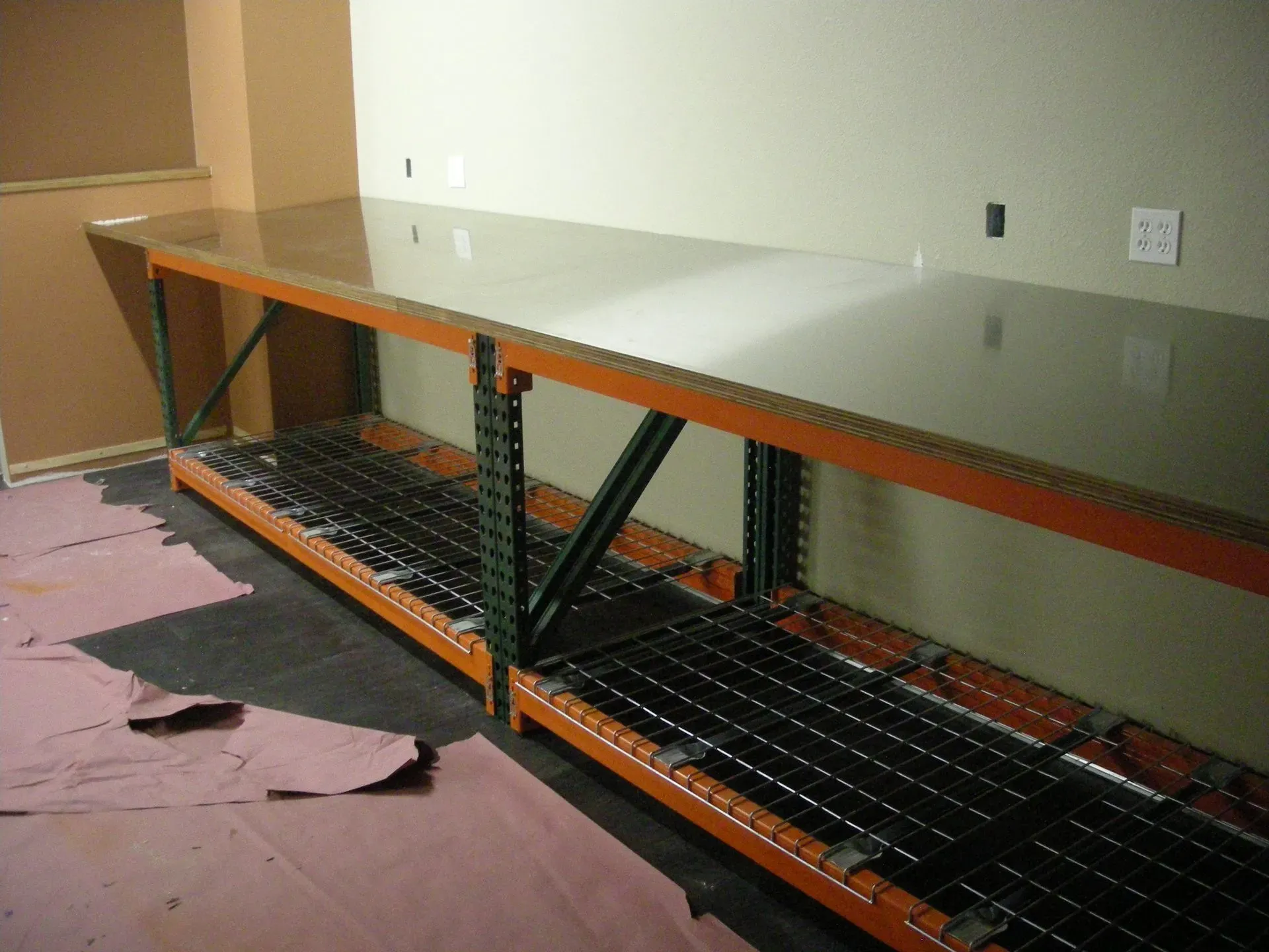 Countertop and open shelving unit under construction, with metal framing and a gray top against a wall.