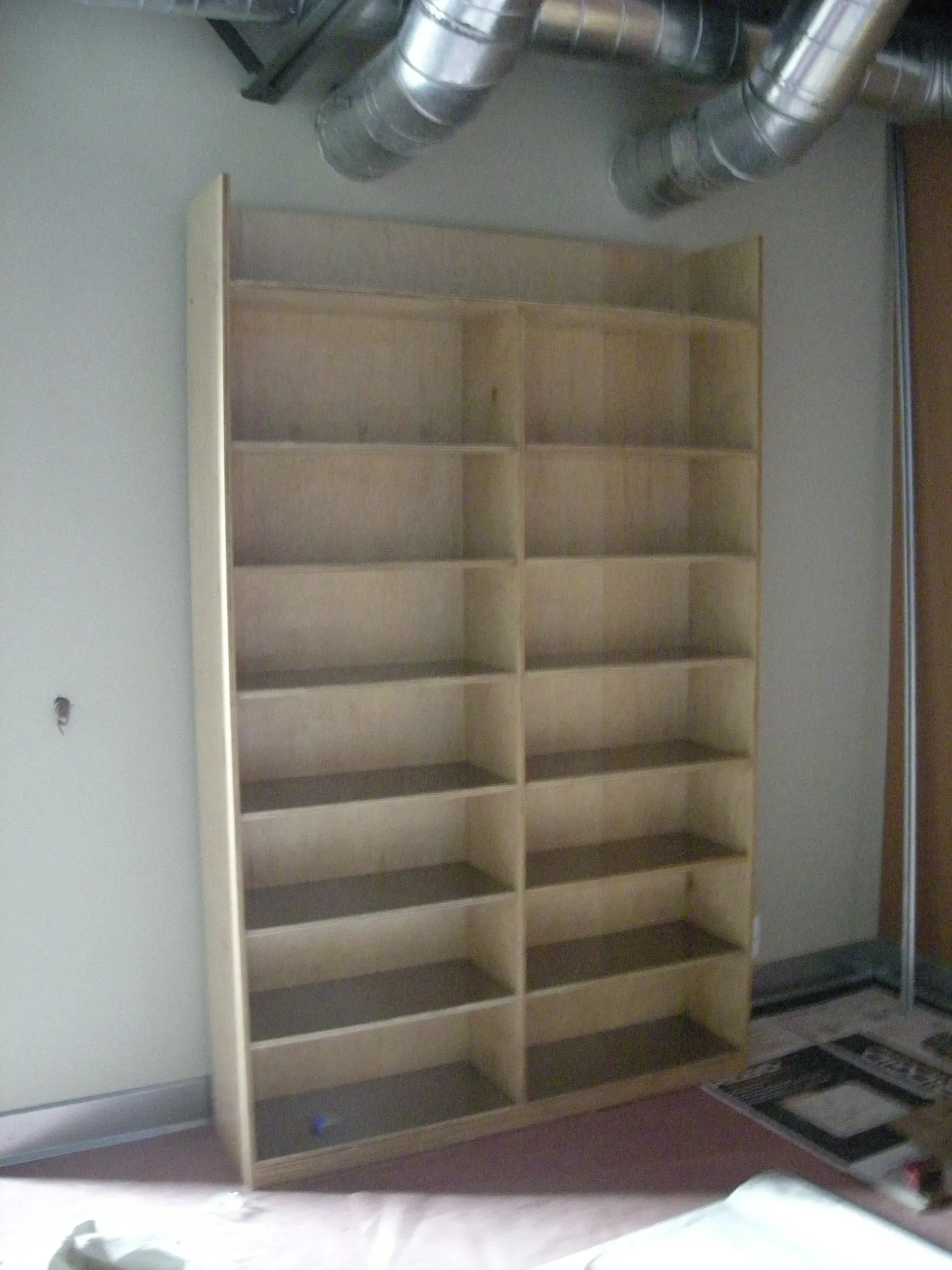 Wooden shelving unit with many compartments against a wall in a storage room