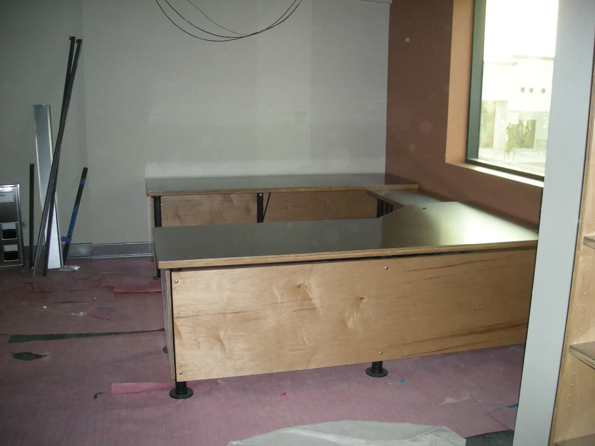 Unfinished wooden platform with open storage compartments in a room under construction.
