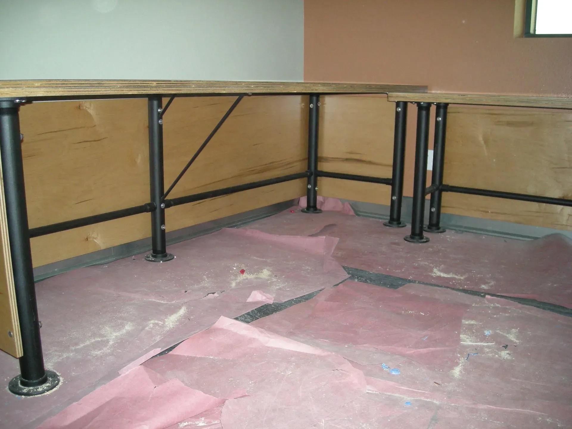 Pink flooring under a table with black metal legs against tan walls