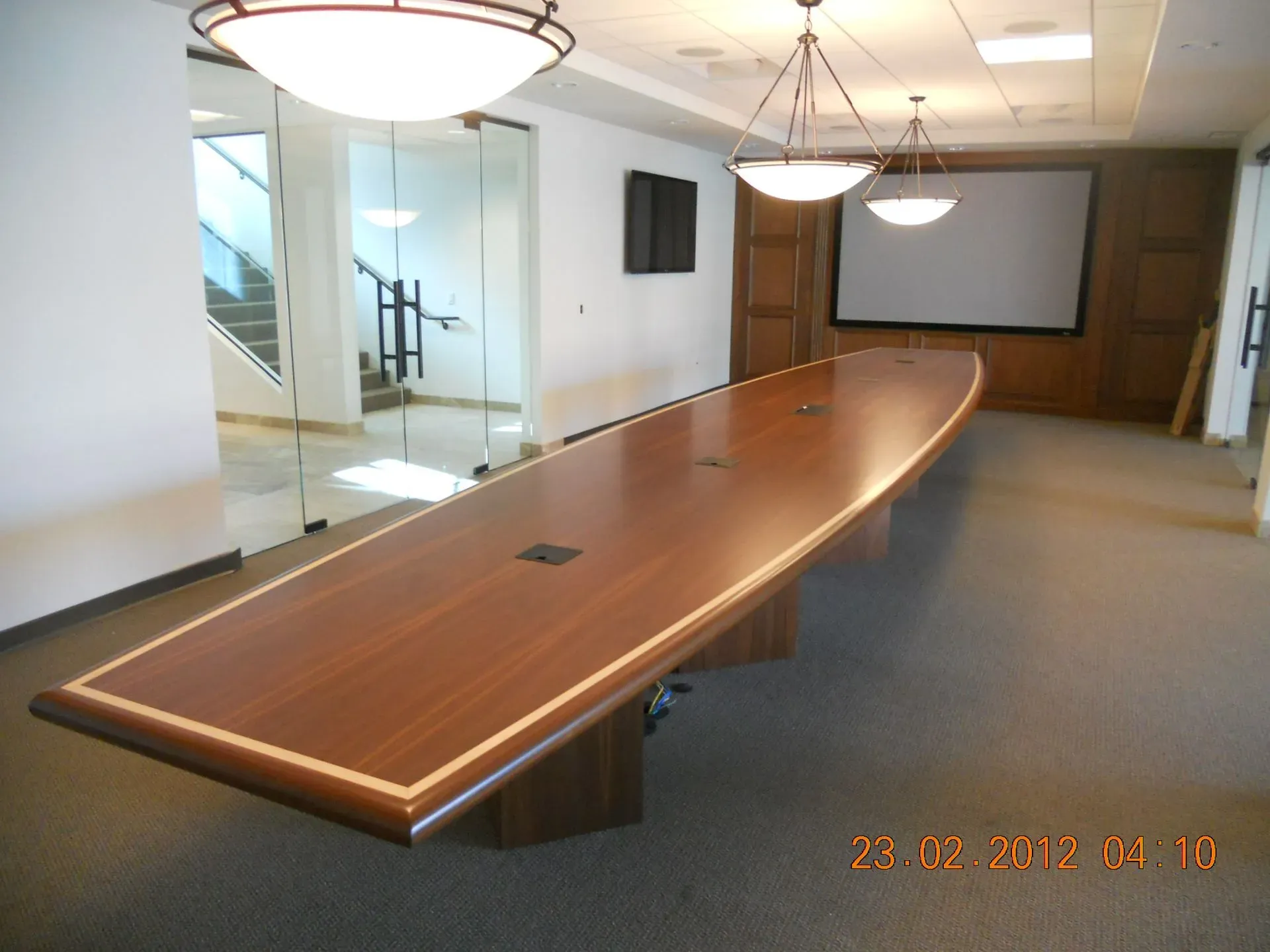 Empty conference room with a long wooden meeting table and overhead lights