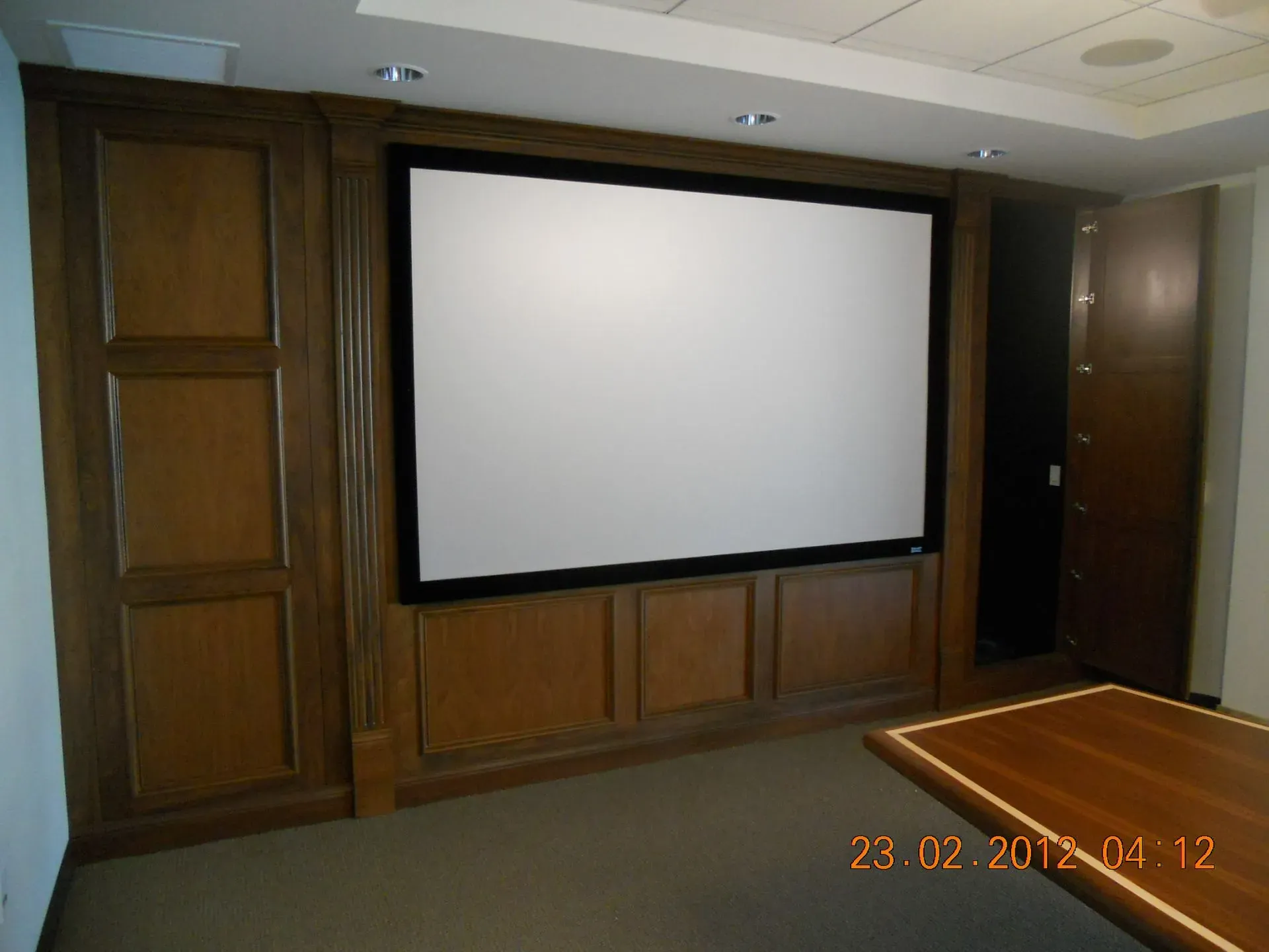 Wood-paneled conference room with a large blank projector screen and a wooden floor