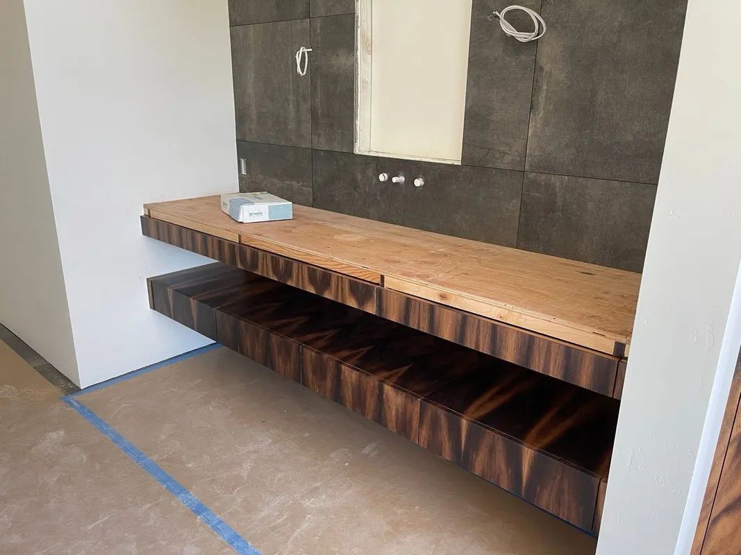 Modern bathroom vanity with wood countertop, dark tile backsplash, and open shelving beneath