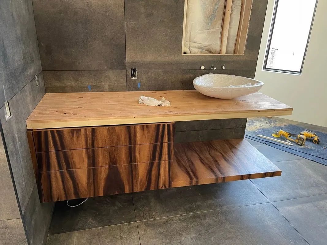 Wooden vanity with bowl sink in a tiled bathroom, featuring a striped fabric skirt beneath the counter