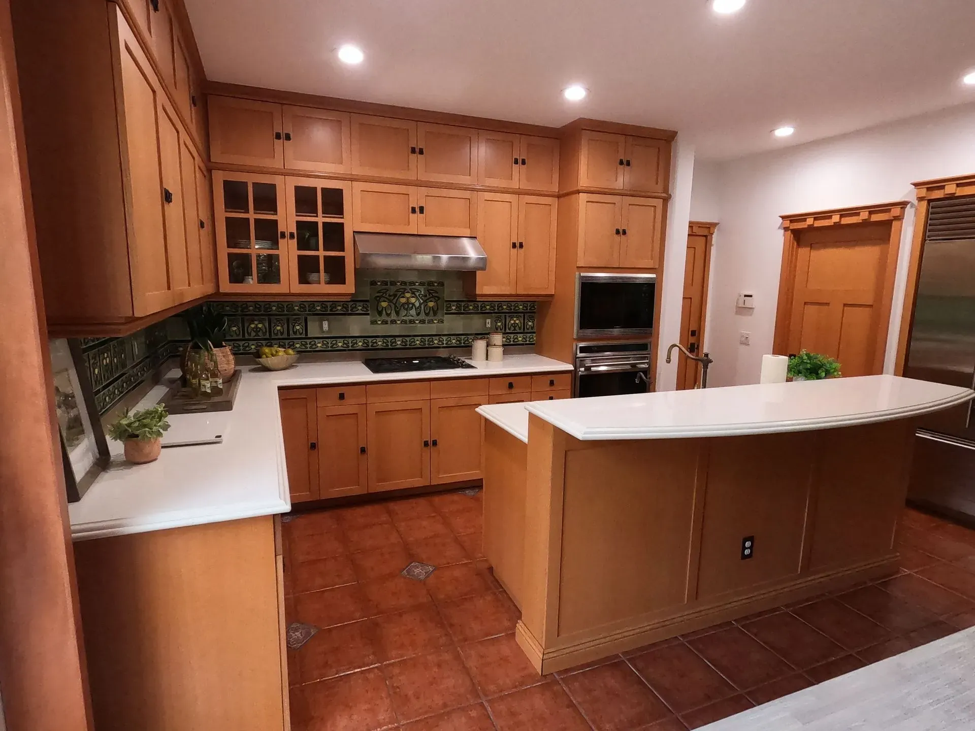 Spacious kitchen with wood cabinets, white countertops, stainless appliances, and a central island with a white top