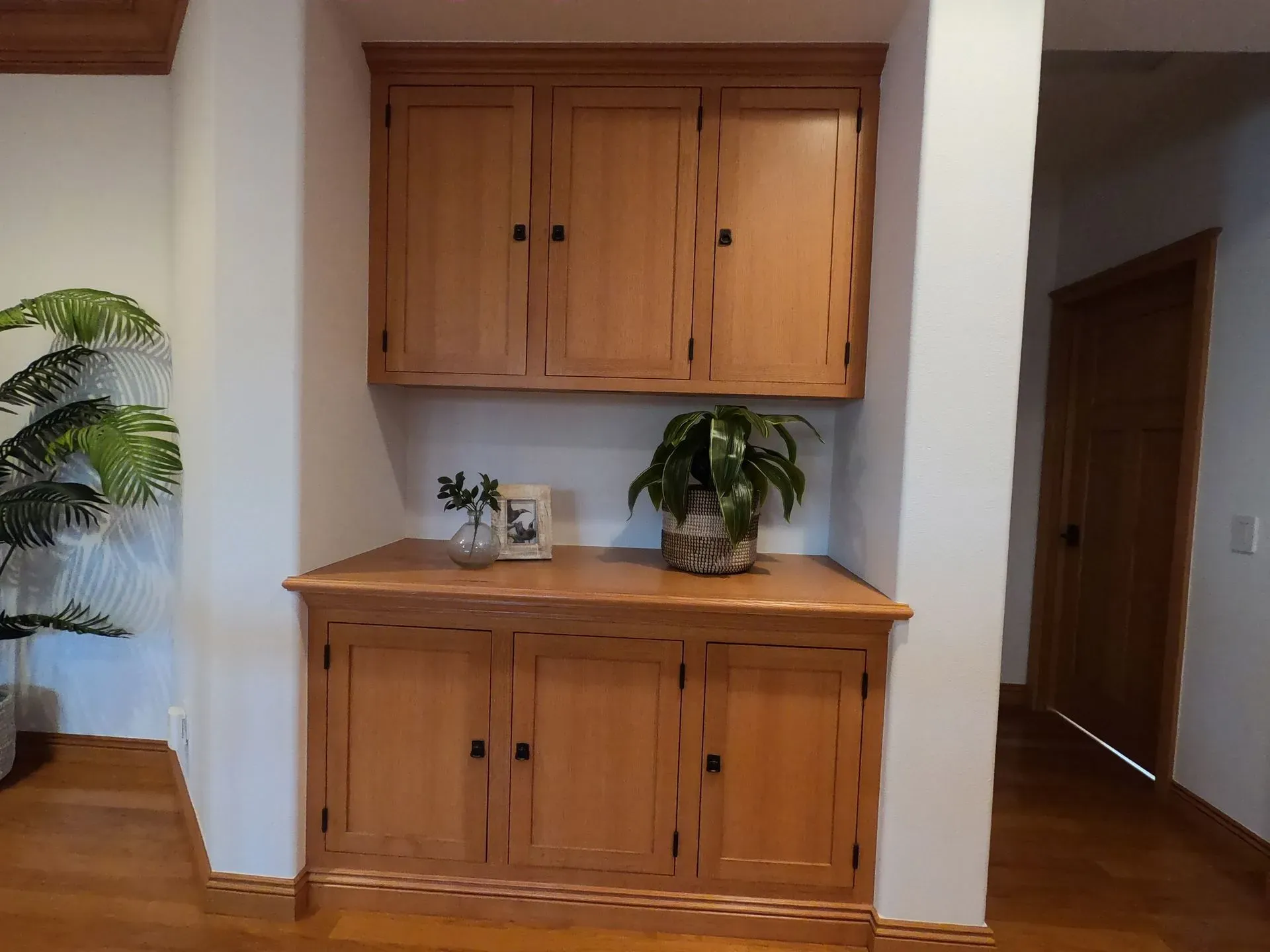 Wooden built-in cabinet with potted plants in a hallway nook