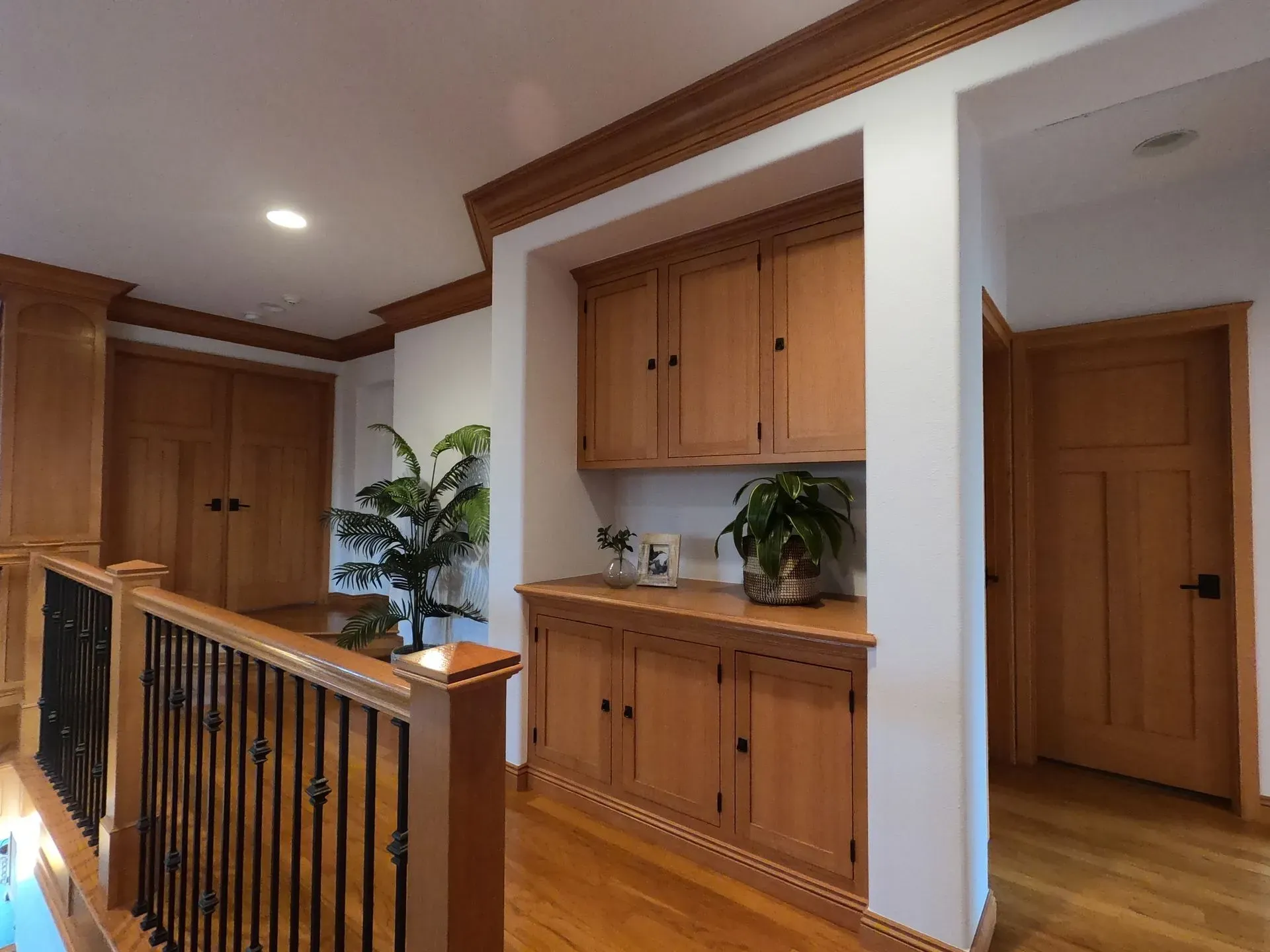 Hallway with wooden built-in cabinets, railings, and white walls in a home interior
