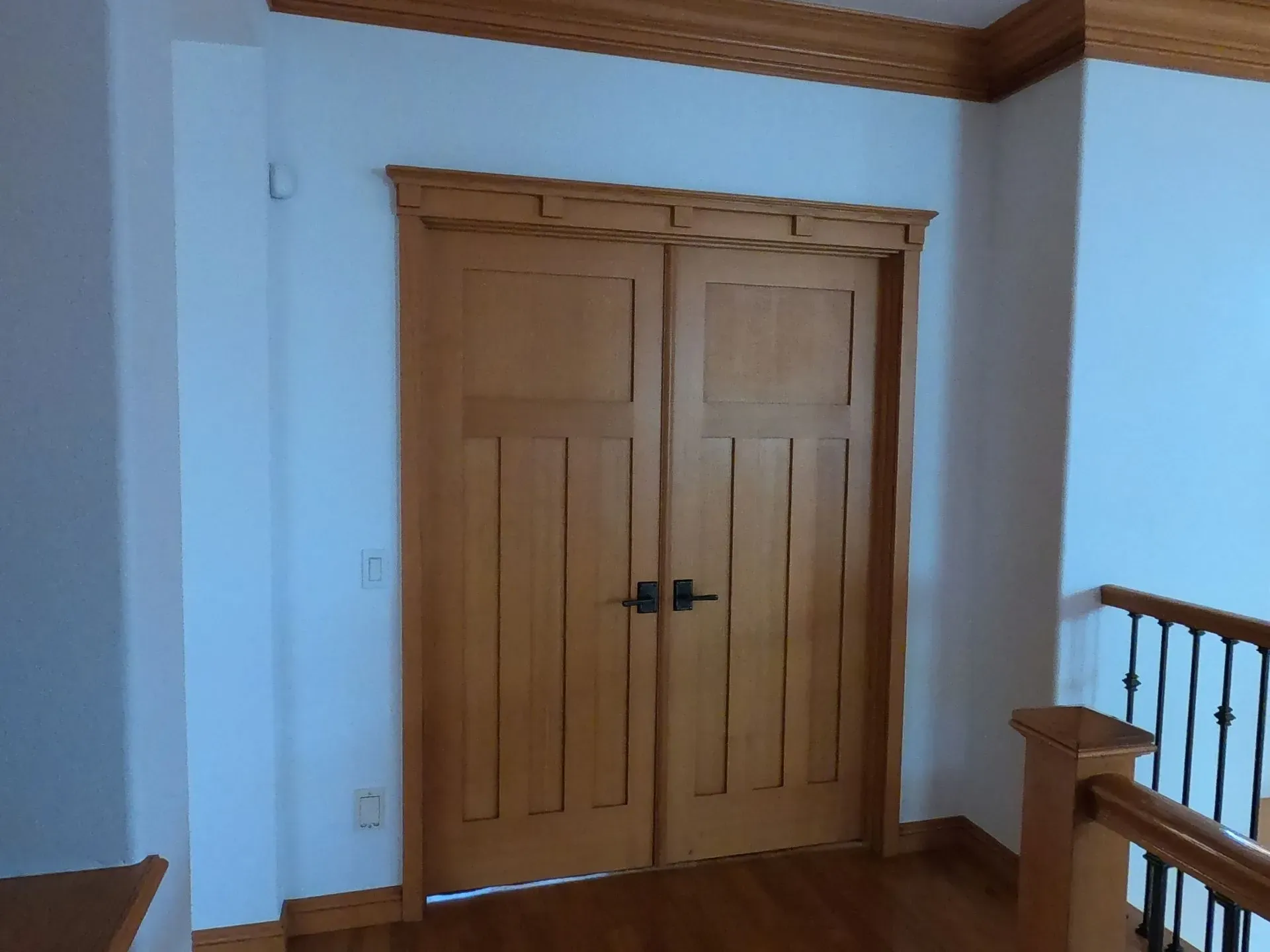 Wooden double closet doors in a room with white walls and wood trim