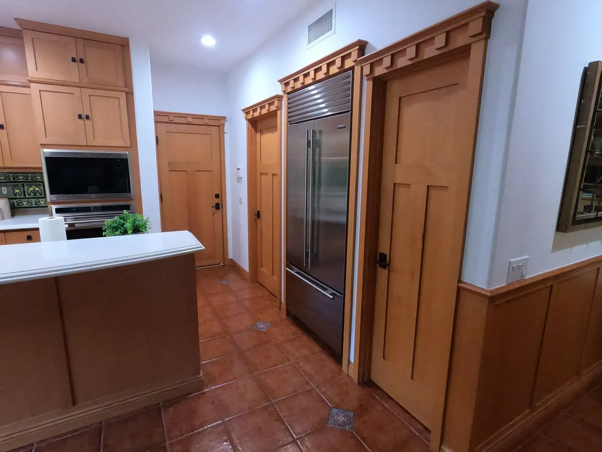 Modern kitchen with wood cabinets, stainless-steel refrigerator, and tiled floor