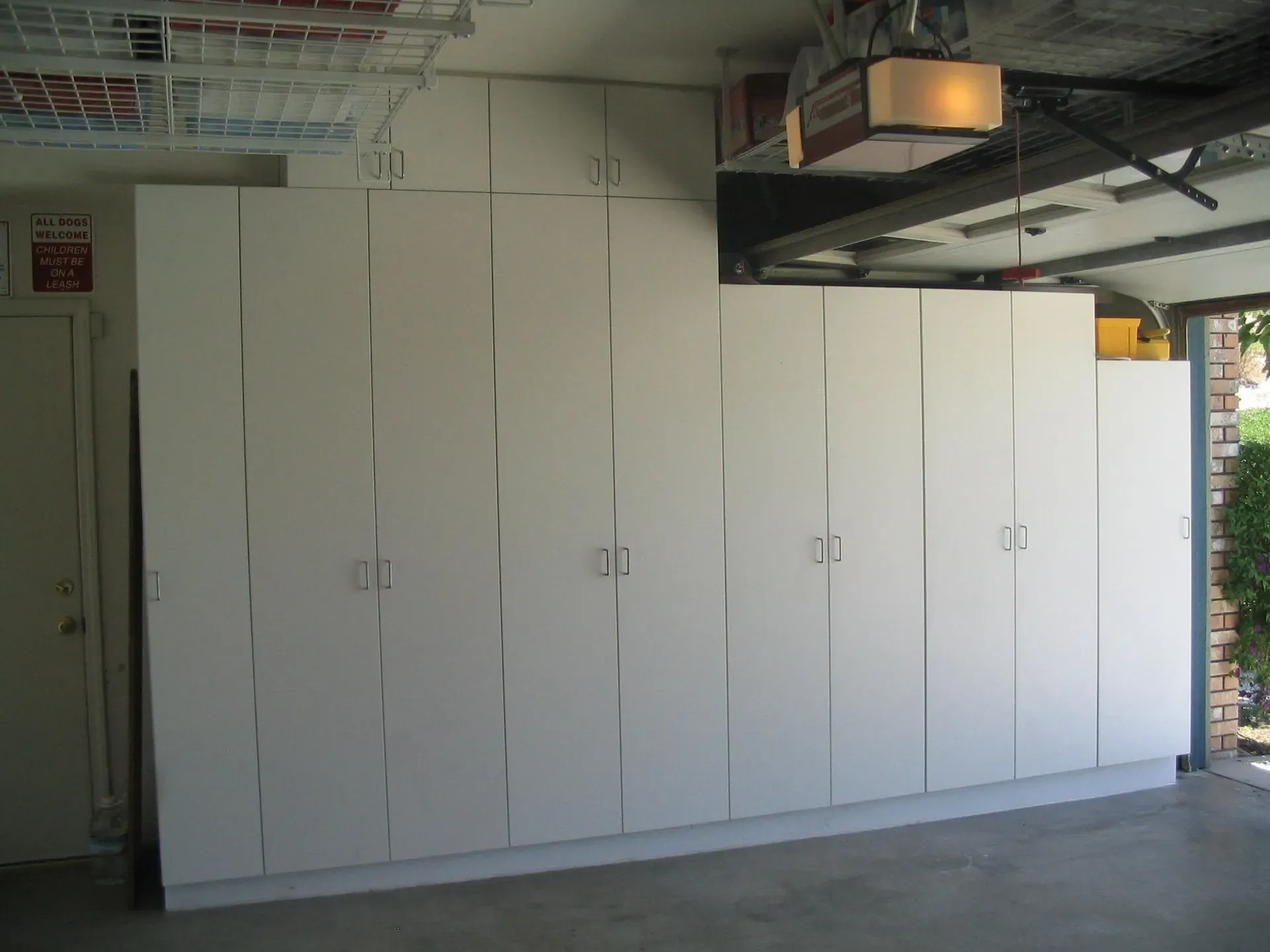 White storage cabinets line an indoor industrial space beneath exposed ceiling pipes.