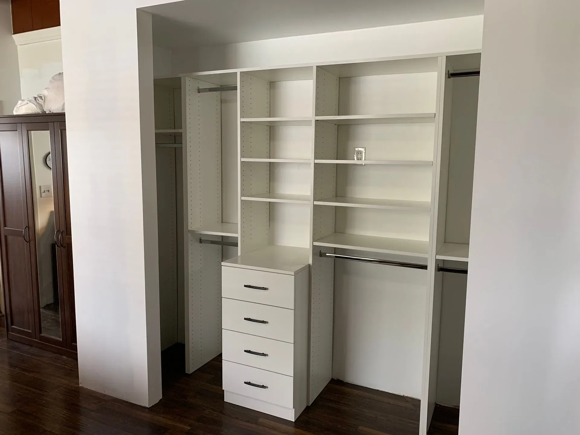 Built-in white closet shelves and drawers in a hardwood-floored room