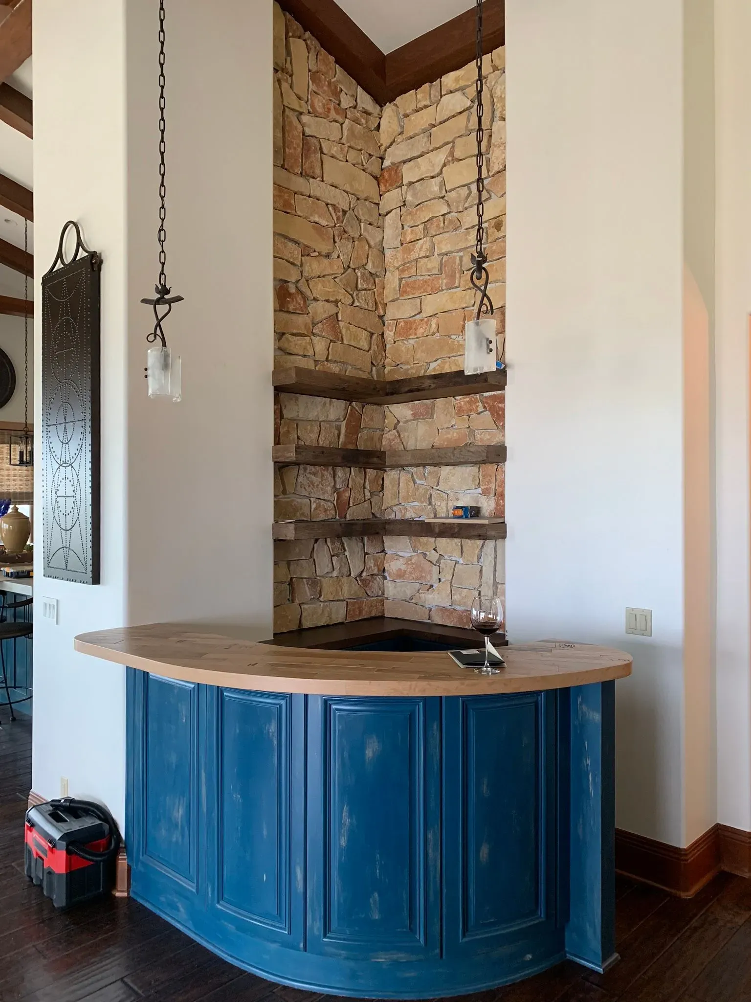 Blue curved bar with wood countertop in a corner alcove of exposed brick and light walls