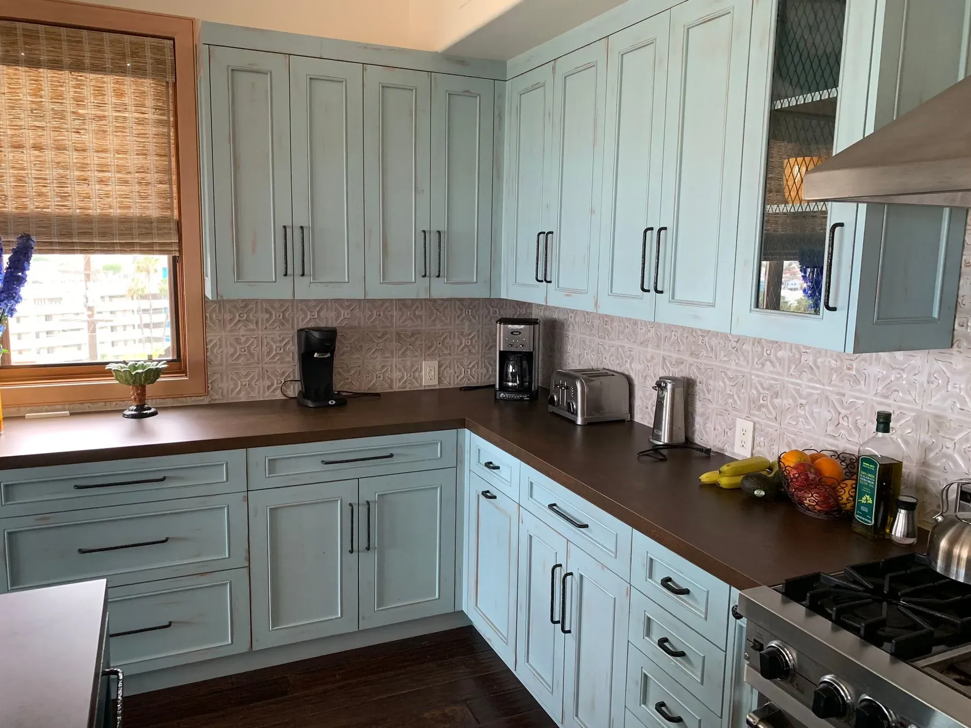 Mint-green kitchen with wood countertops, white tile backsplash, and a window over the sink