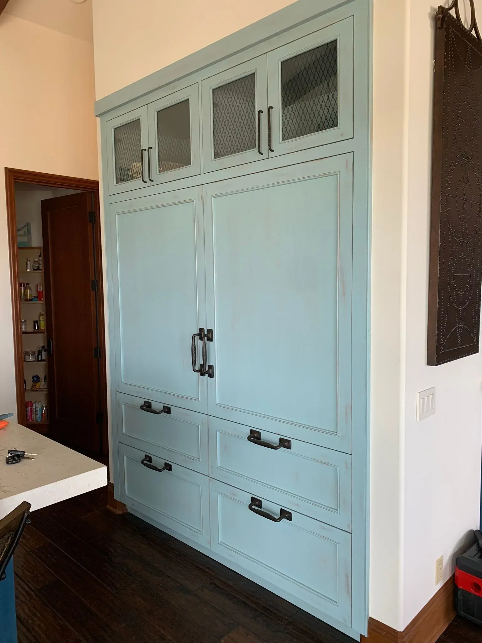 Light blue built-in cabinet with mesh doors in a room beside a doorway and white wall