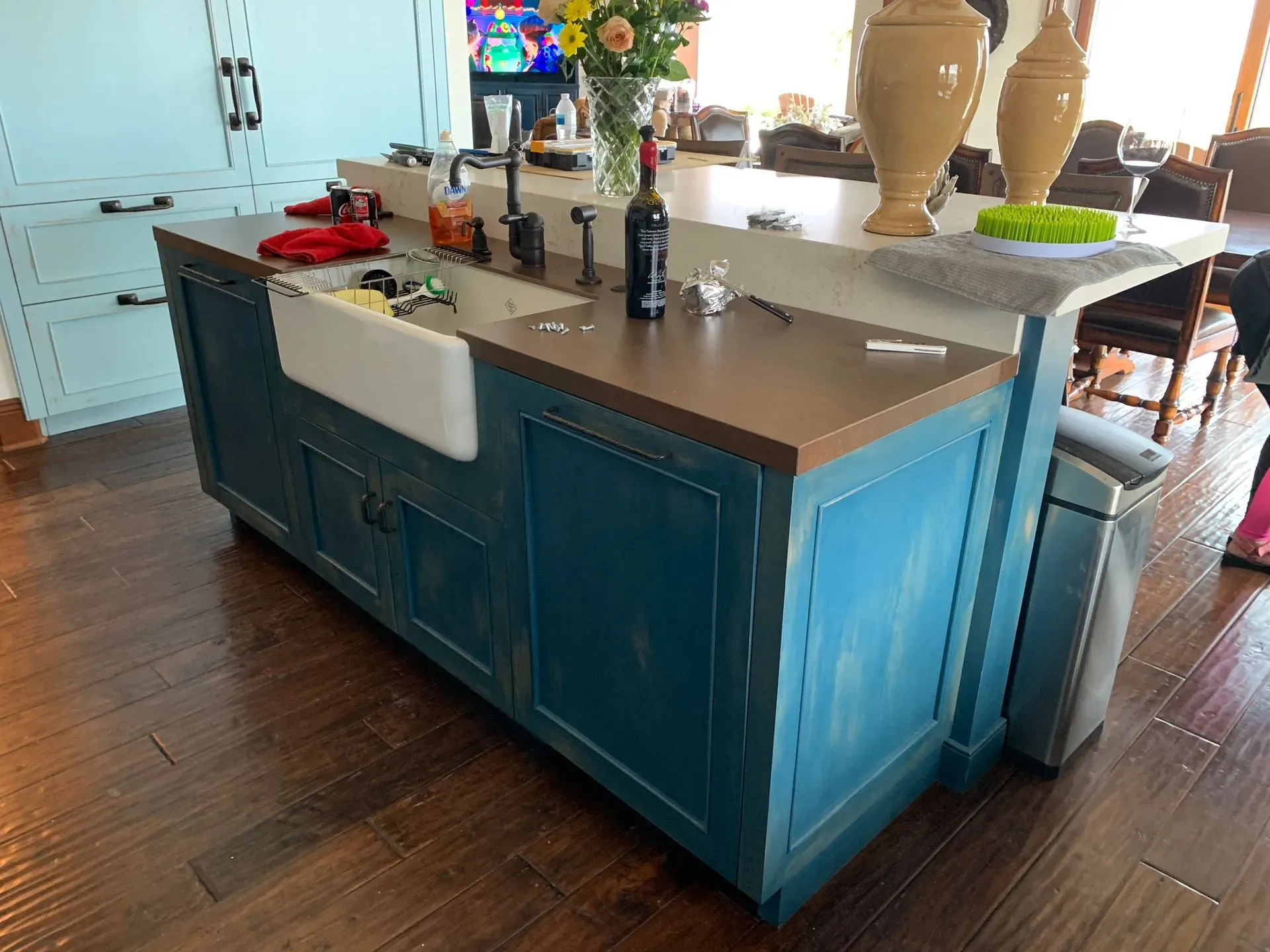 Kitchen island with blue cabinets and white countertop in a hardwood-floored kitchen