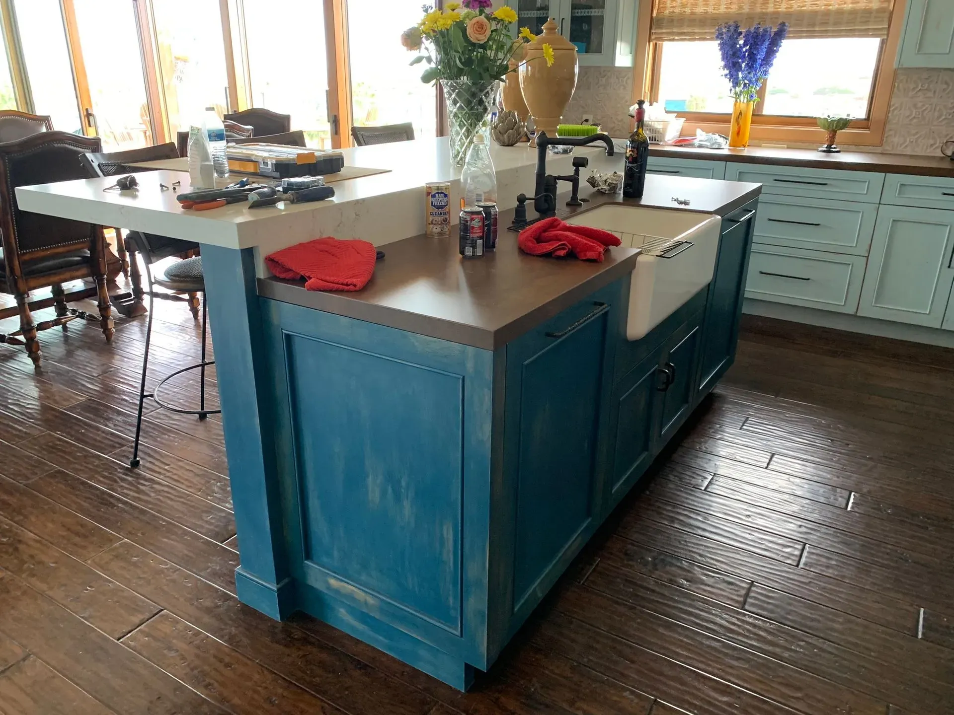 Blue kitchen island with red napkins in a bright farmhouse kitchen