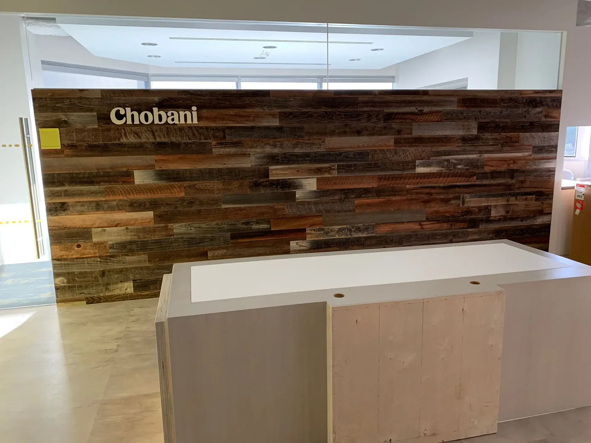 Chobani lobby with wood accent wall and white reception desk in a bright office space