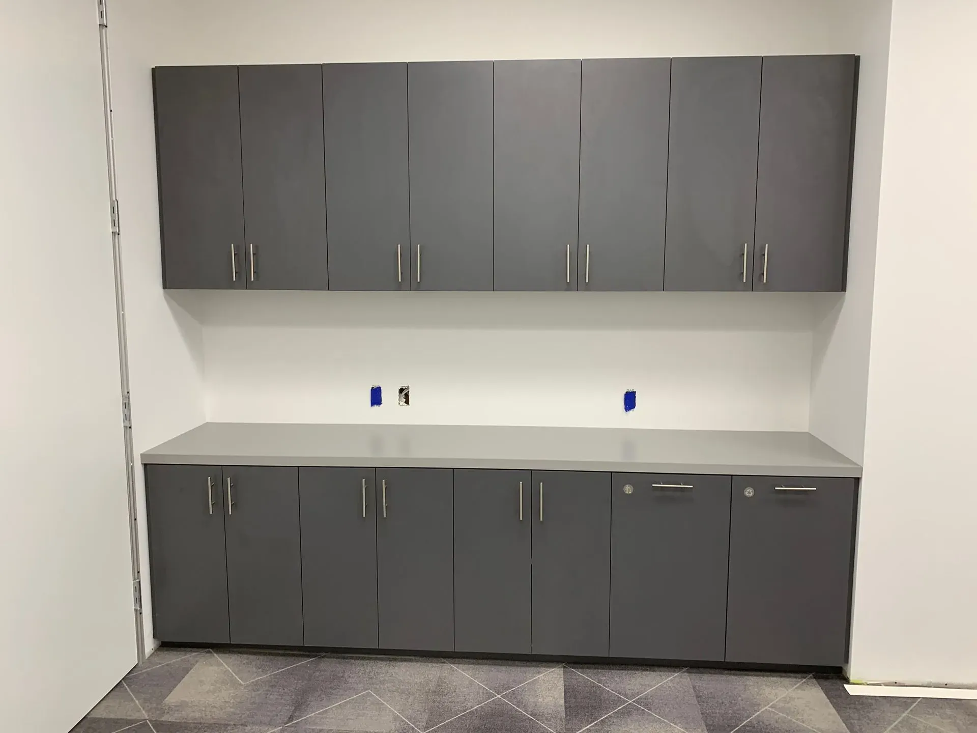 Gray cabinets and countertop in a plain room with white walls and power outlets