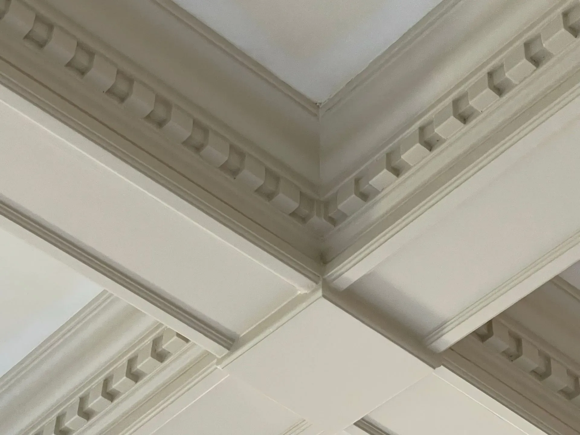 Close-up of ornate white ceiling molding with decorative trim and intersecting beams