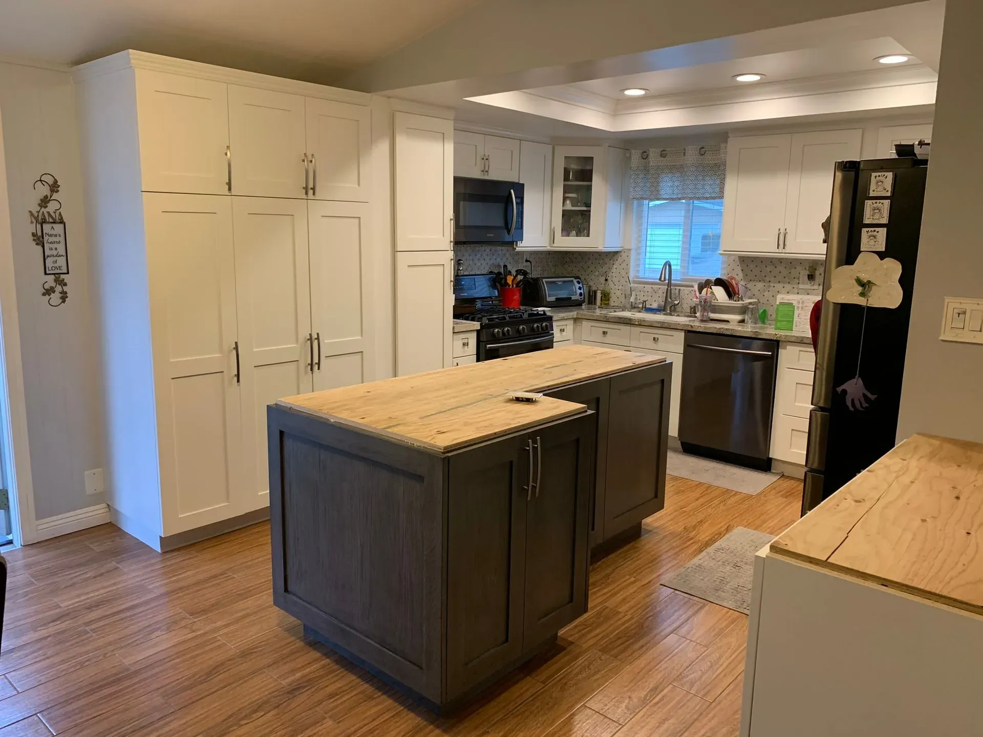 Bright kitchen with white cabinets, wood island, stainless appliances, and hardwood floors