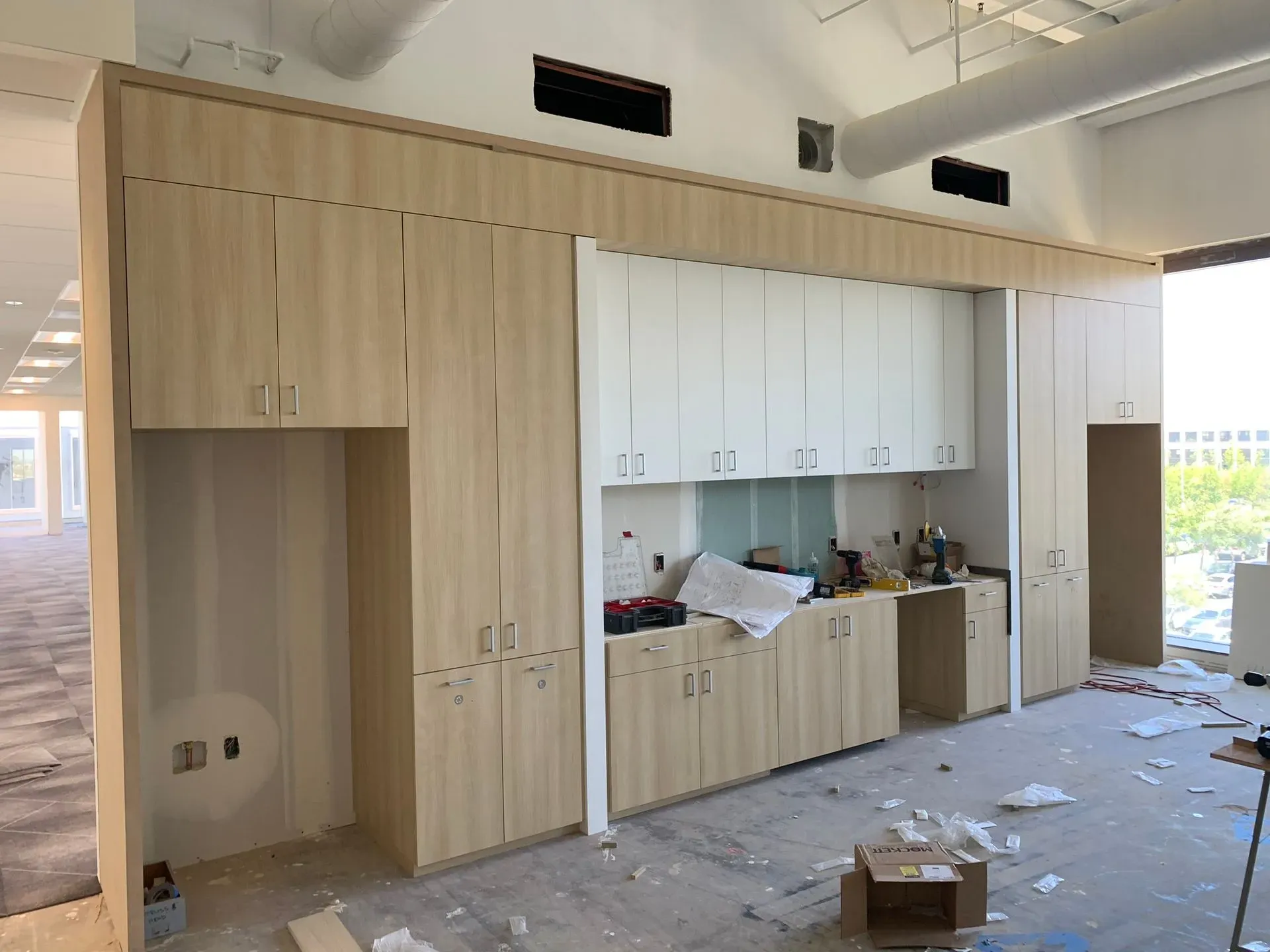 Unfinished room with wood cabinets and white built-ins, debris on the floor, and open wall niches