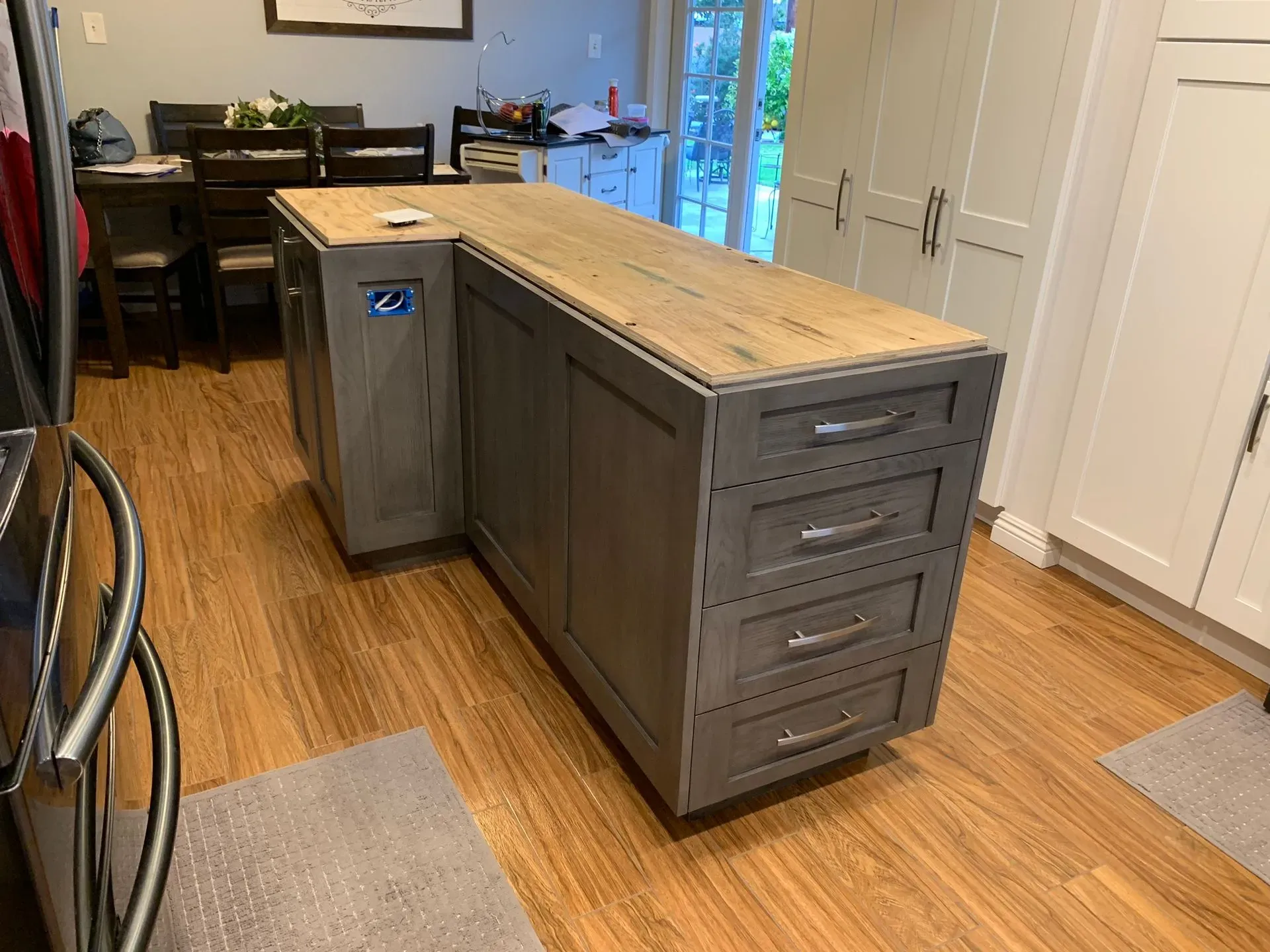 Gray kitchen island with wood countertop in a home kitchen, next to white cabinets and a table