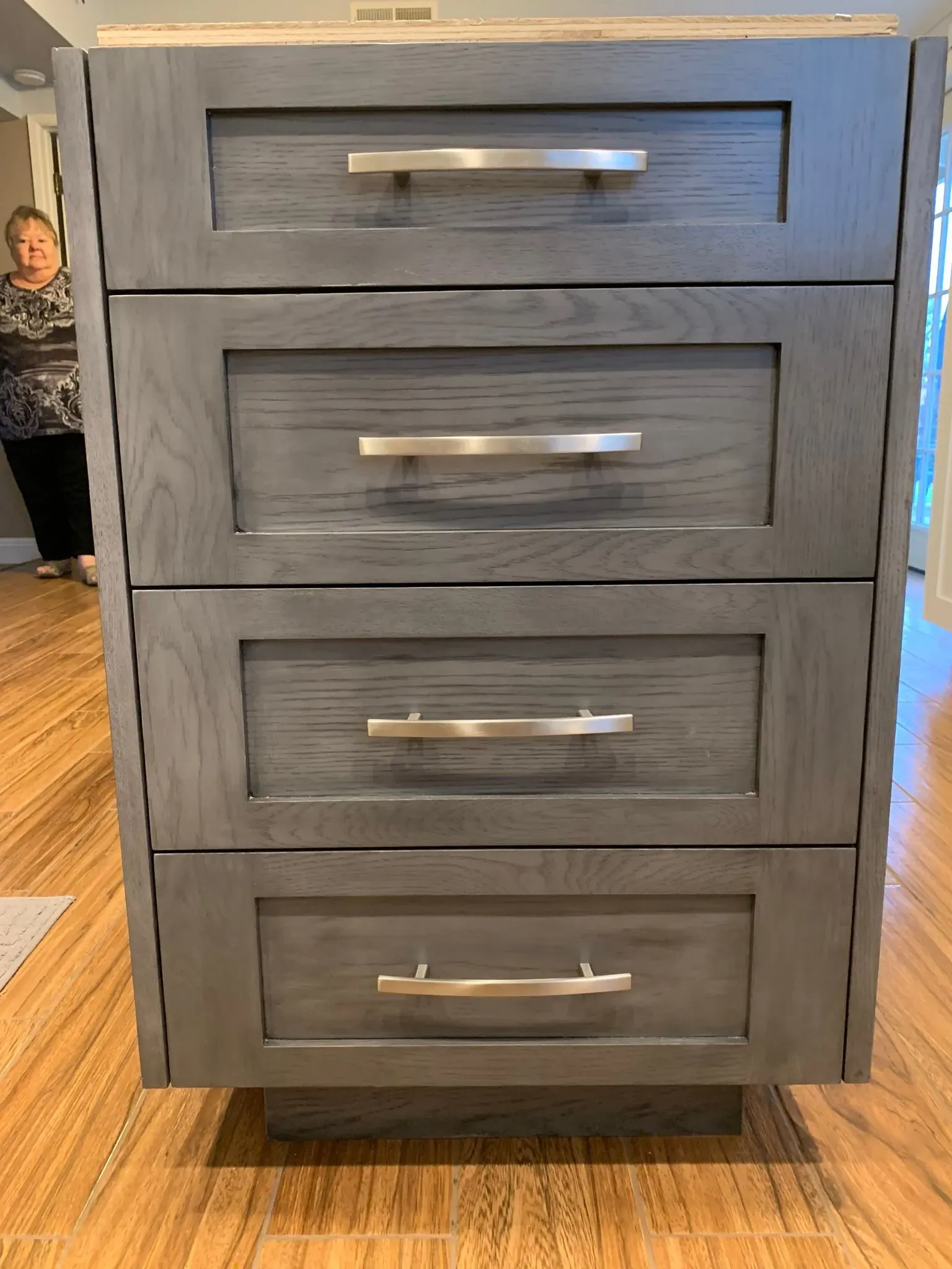 Gray four-drawer dresser with silver handles on a wooden floor in a home interior