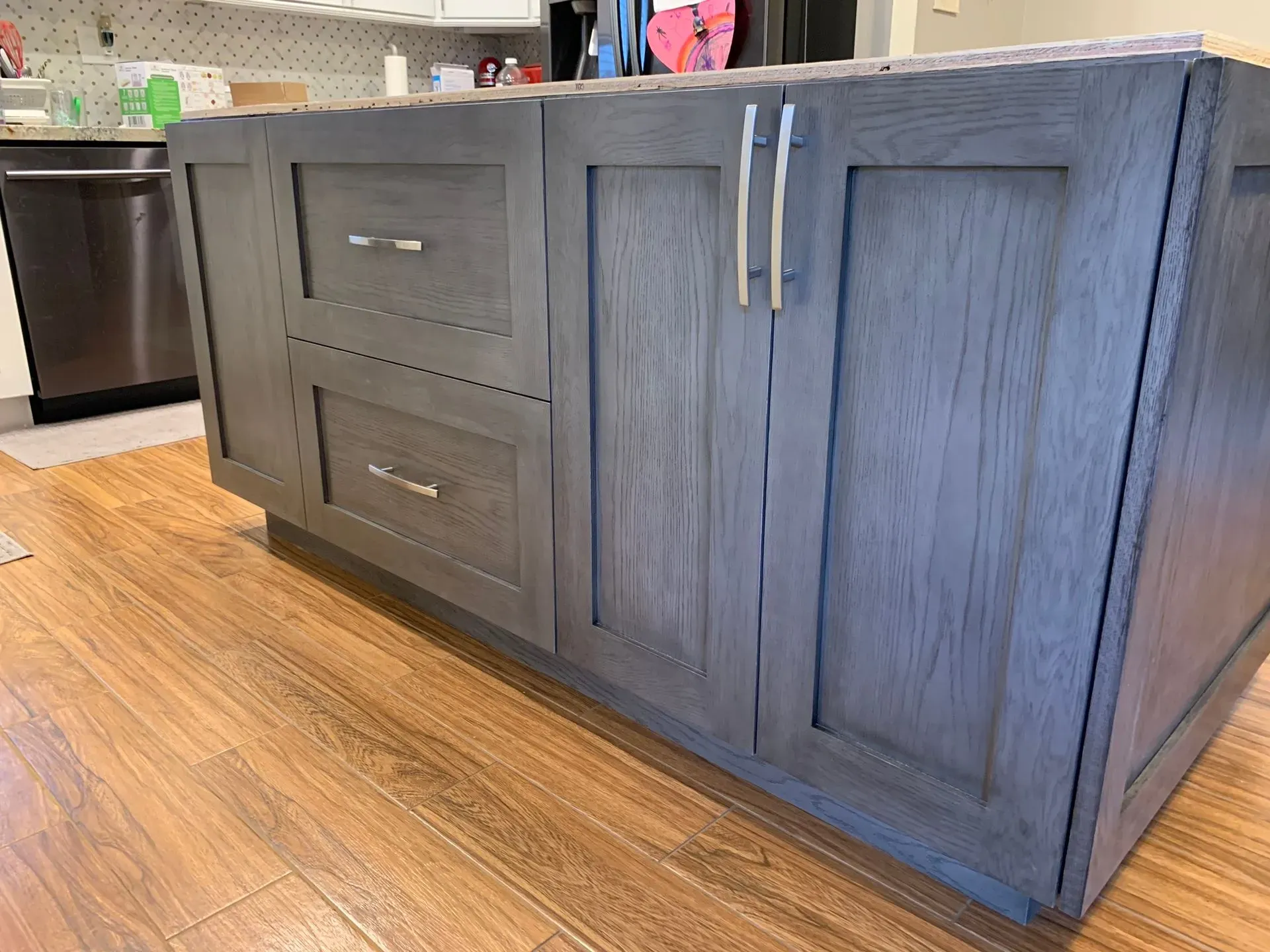 Gray kitchen island cabinets with drawers and double doors on a wood floor in a kitchen