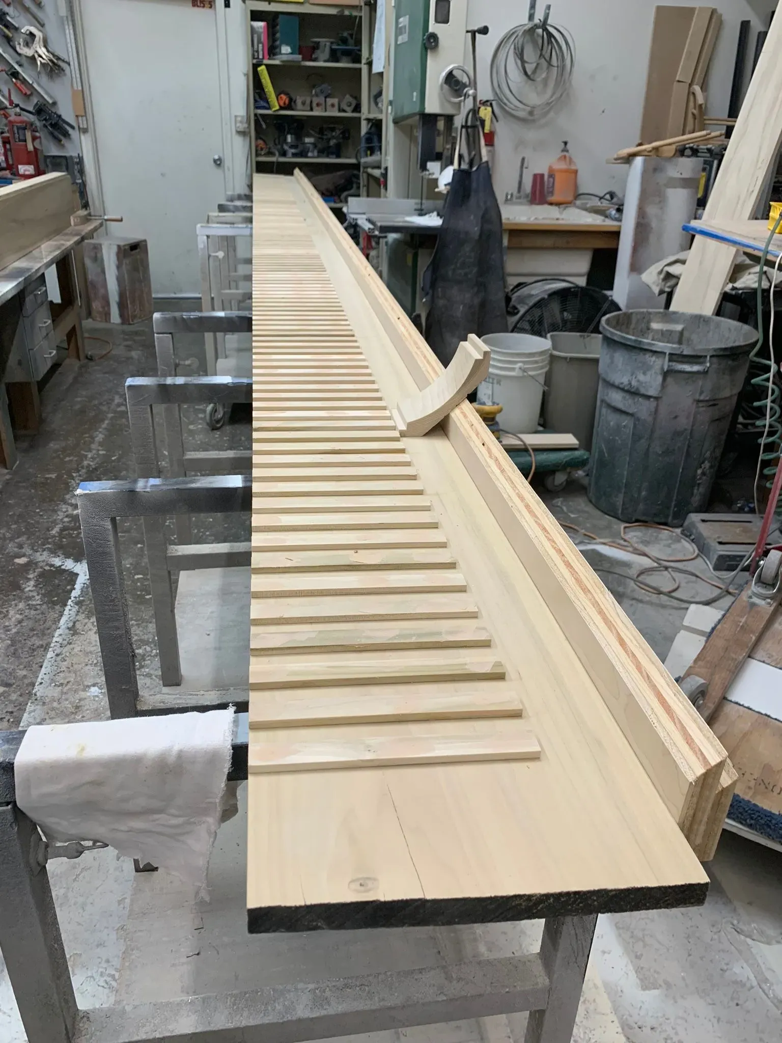 Woodworker shaping a long wooden panel with evenly spaced slats in a workshop