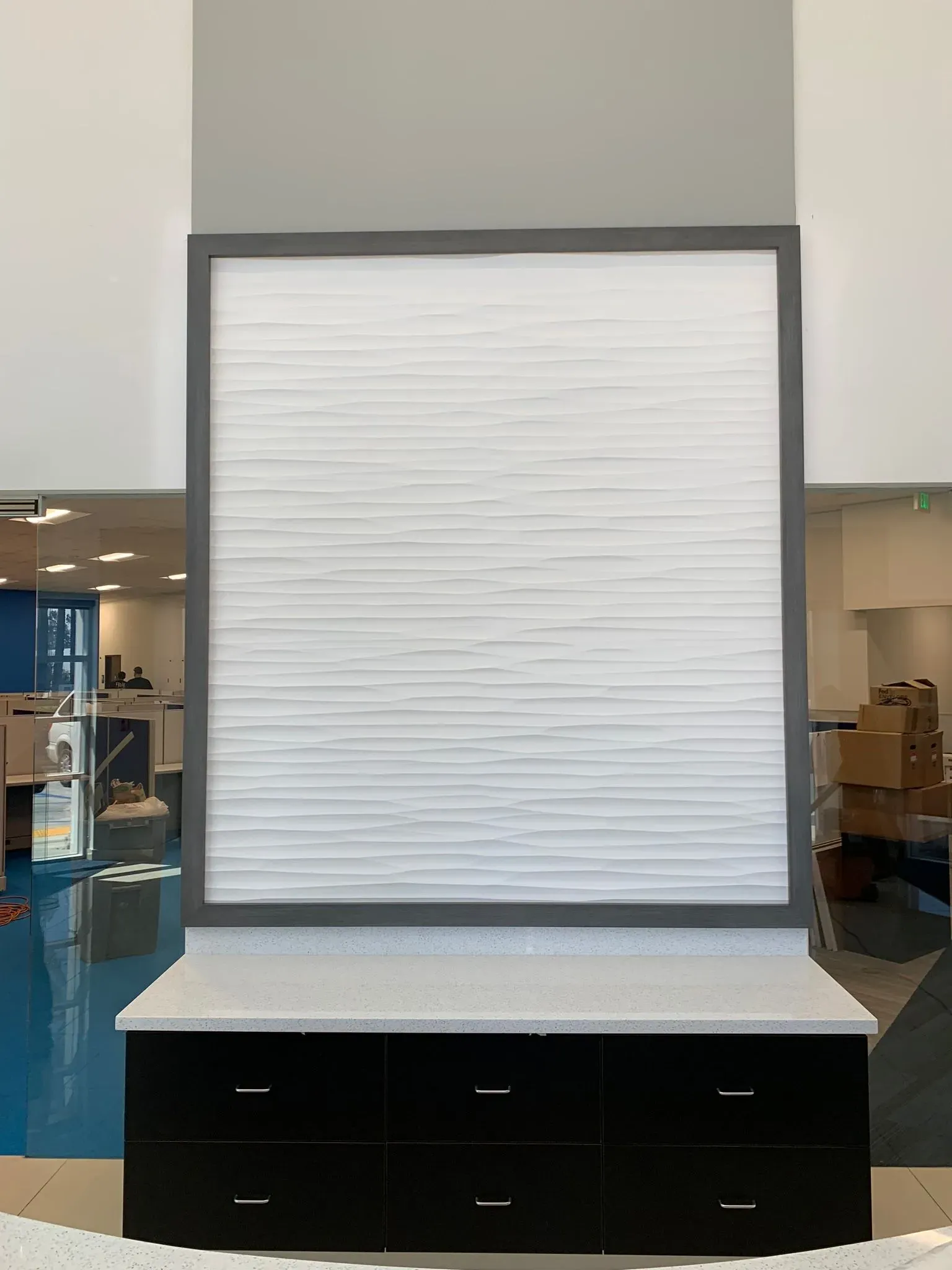 Large white slatwall display board above a black cabinet in a store interior.