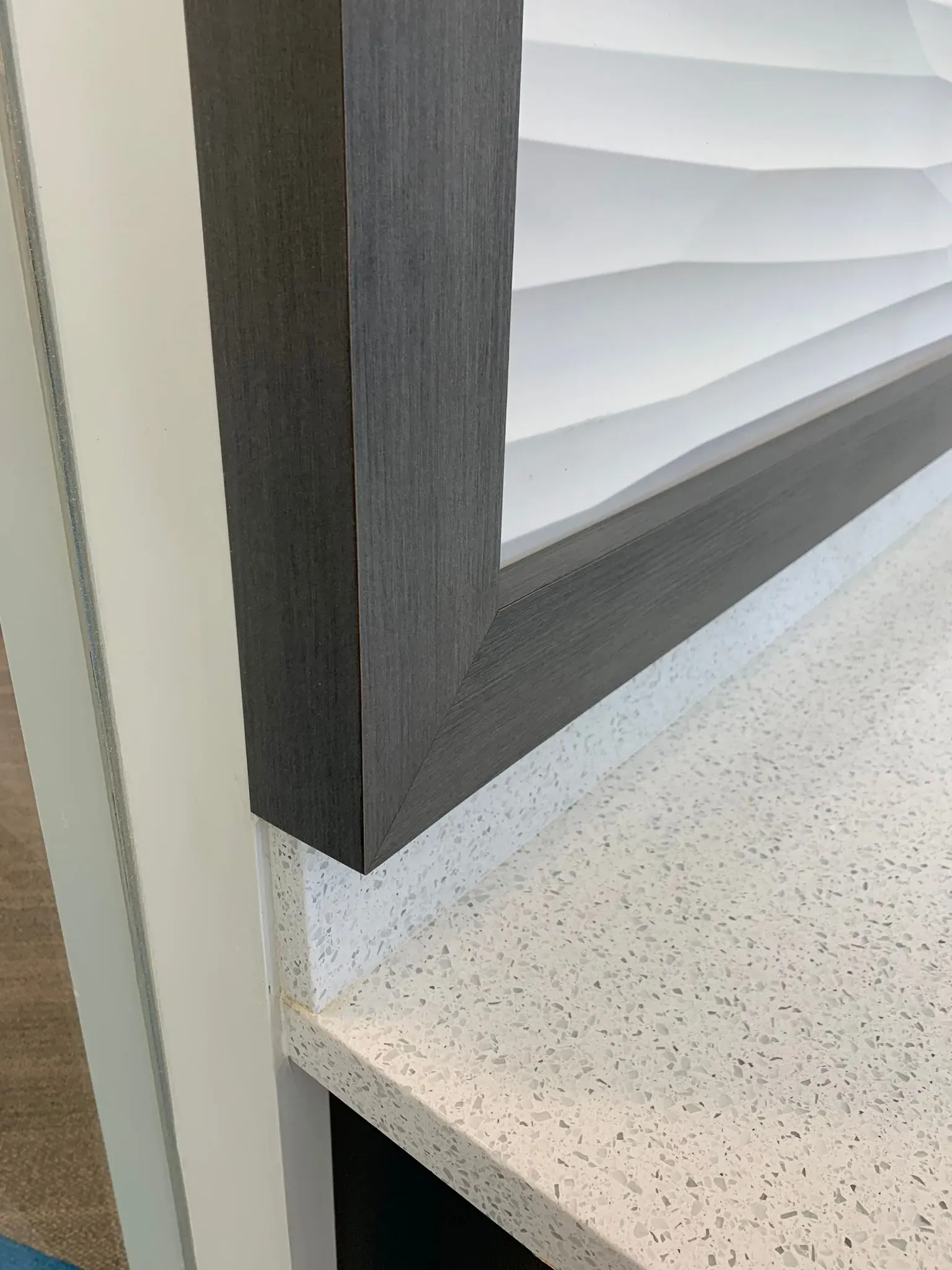 Close-up of a gray window frame above a speckled white countertop