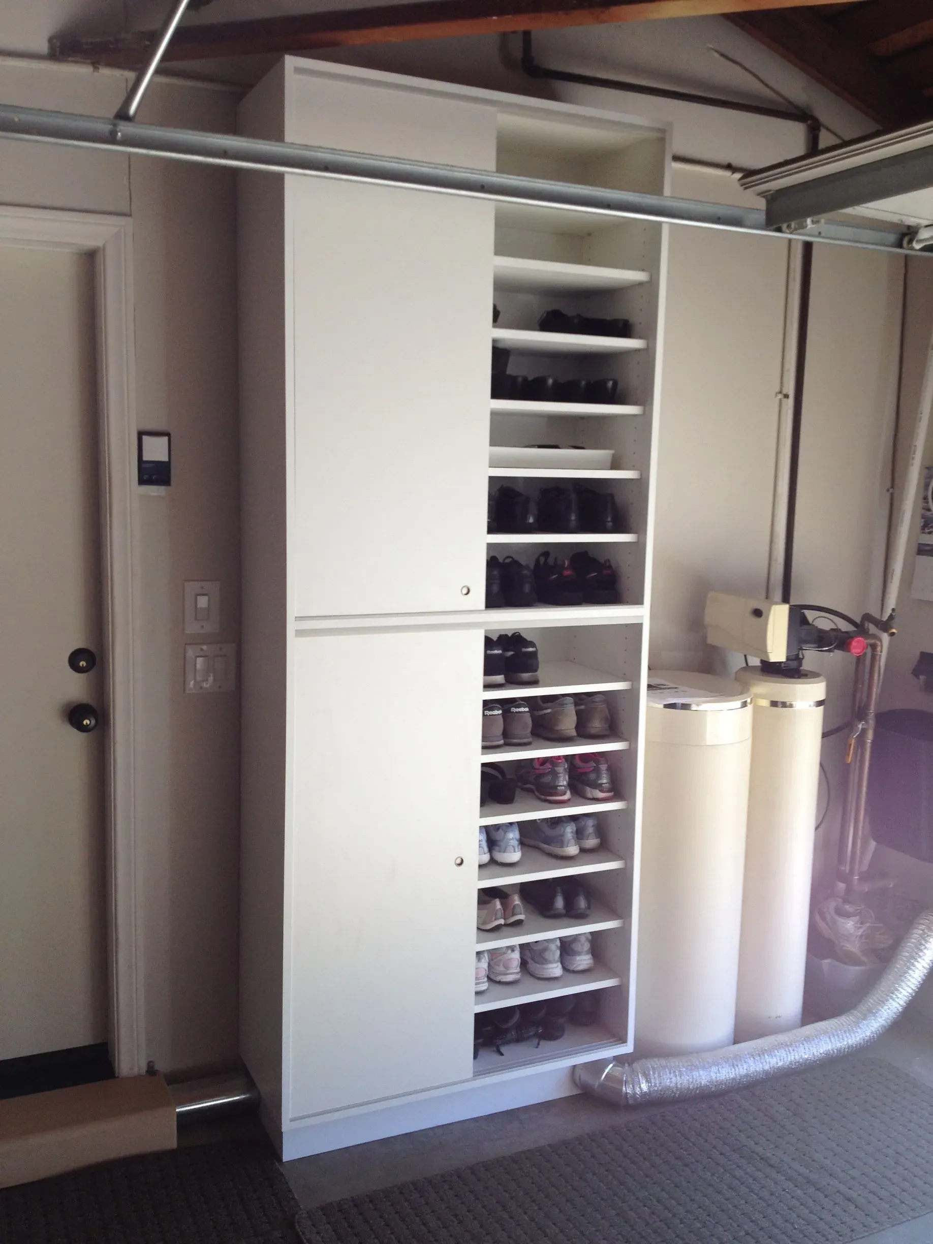 Garage storage cabinets with shelves, white tanks, and a flexible hose attached.