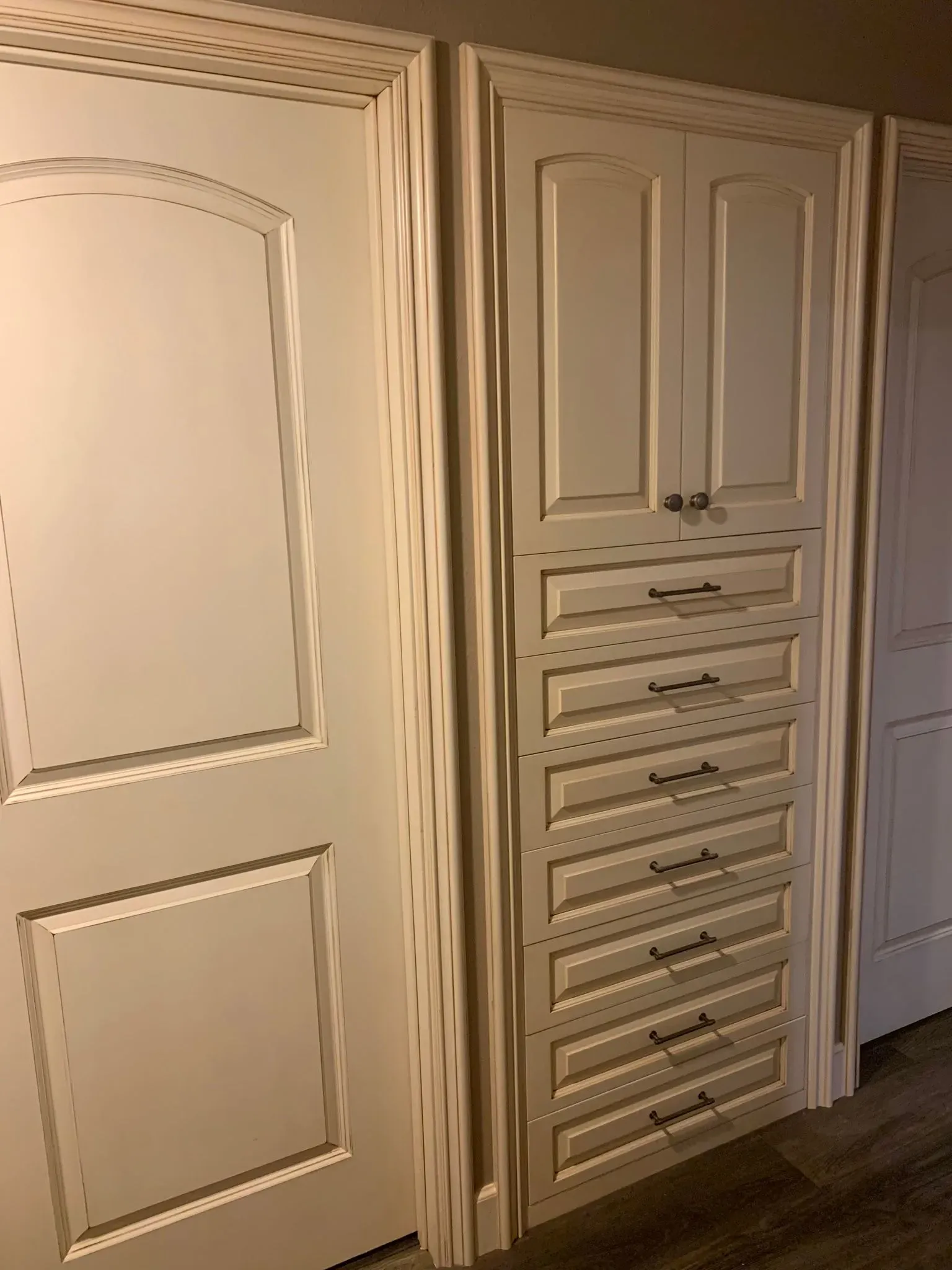 Beige built-in closet with paneled doors and drawers in a hallway or bedroom