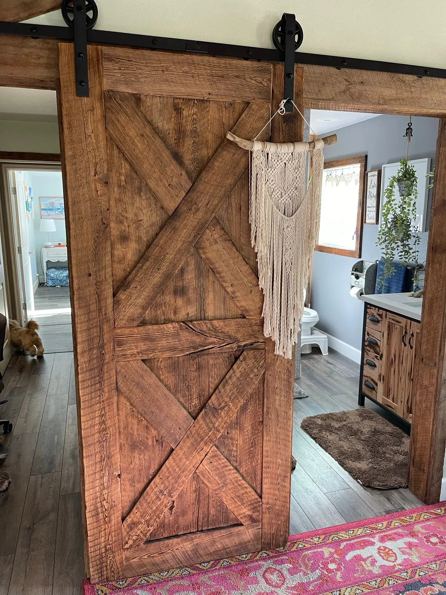 Rustic barn-style sliding wooden door with diagonal planks and a hanging macramé decoration in a cozy room