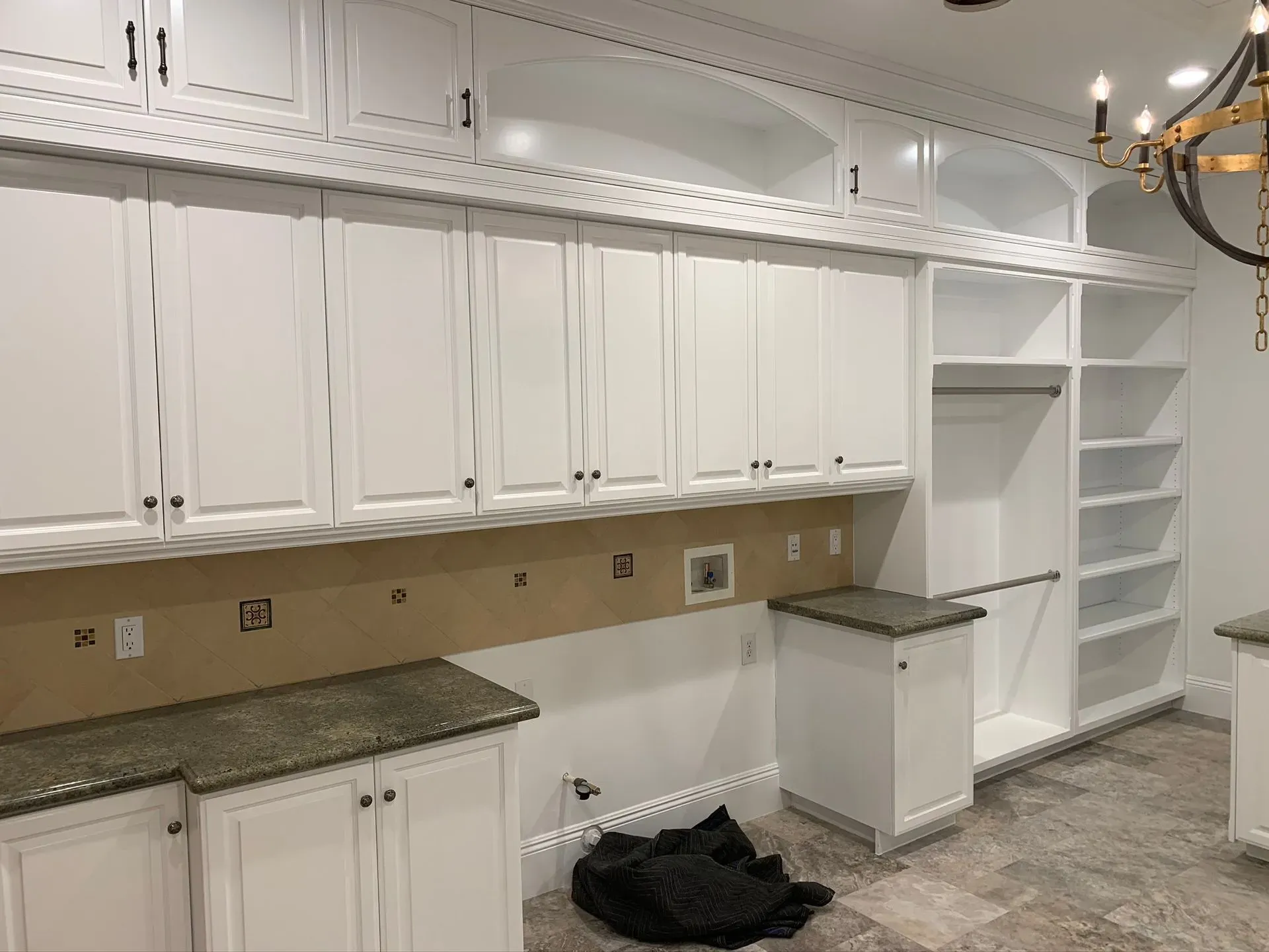 White walk-in closet with built-in cabinets, shelves, granite countertop, and chandelier lighting