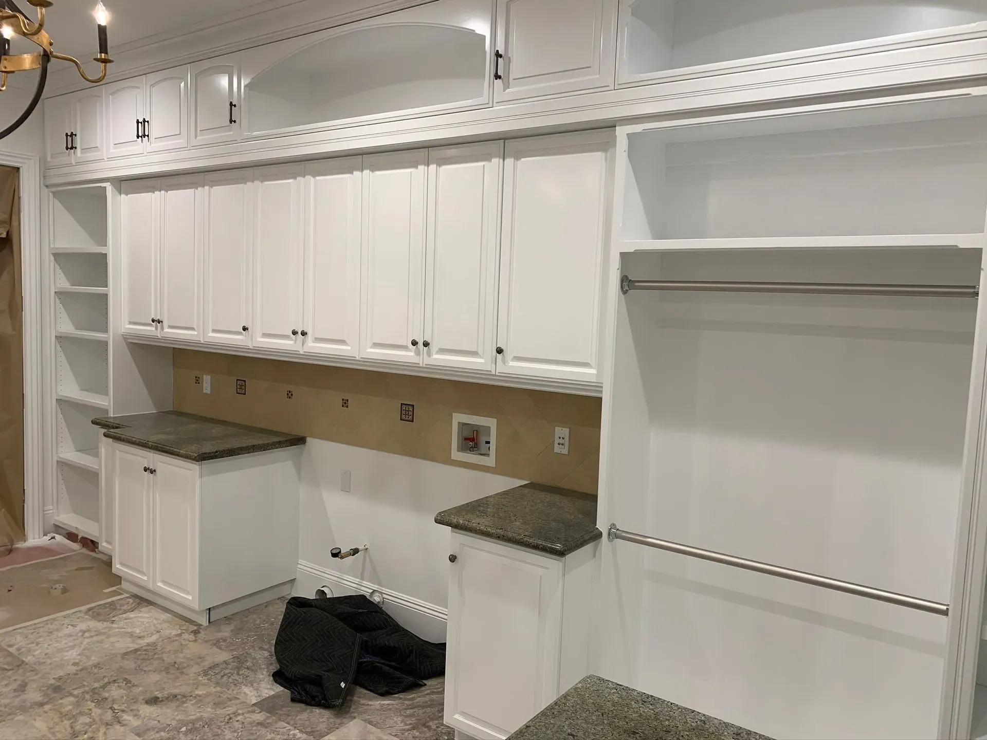 White built-in kitchen cabinets with granite counters in a renovated room under construction