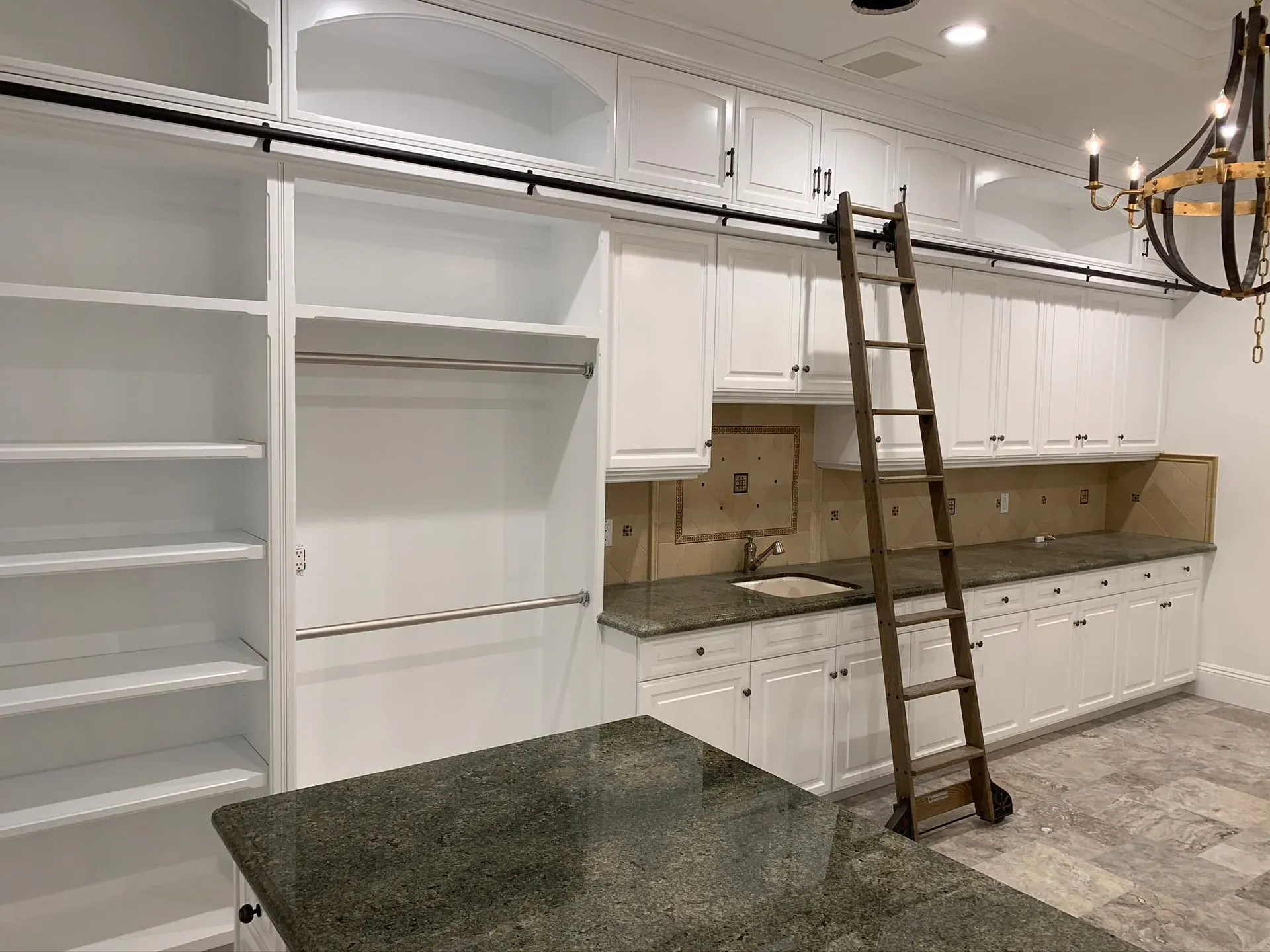 Kitchen remodel with white cabinets, open shelving, and a ladder beneath exposed ceiling wiring