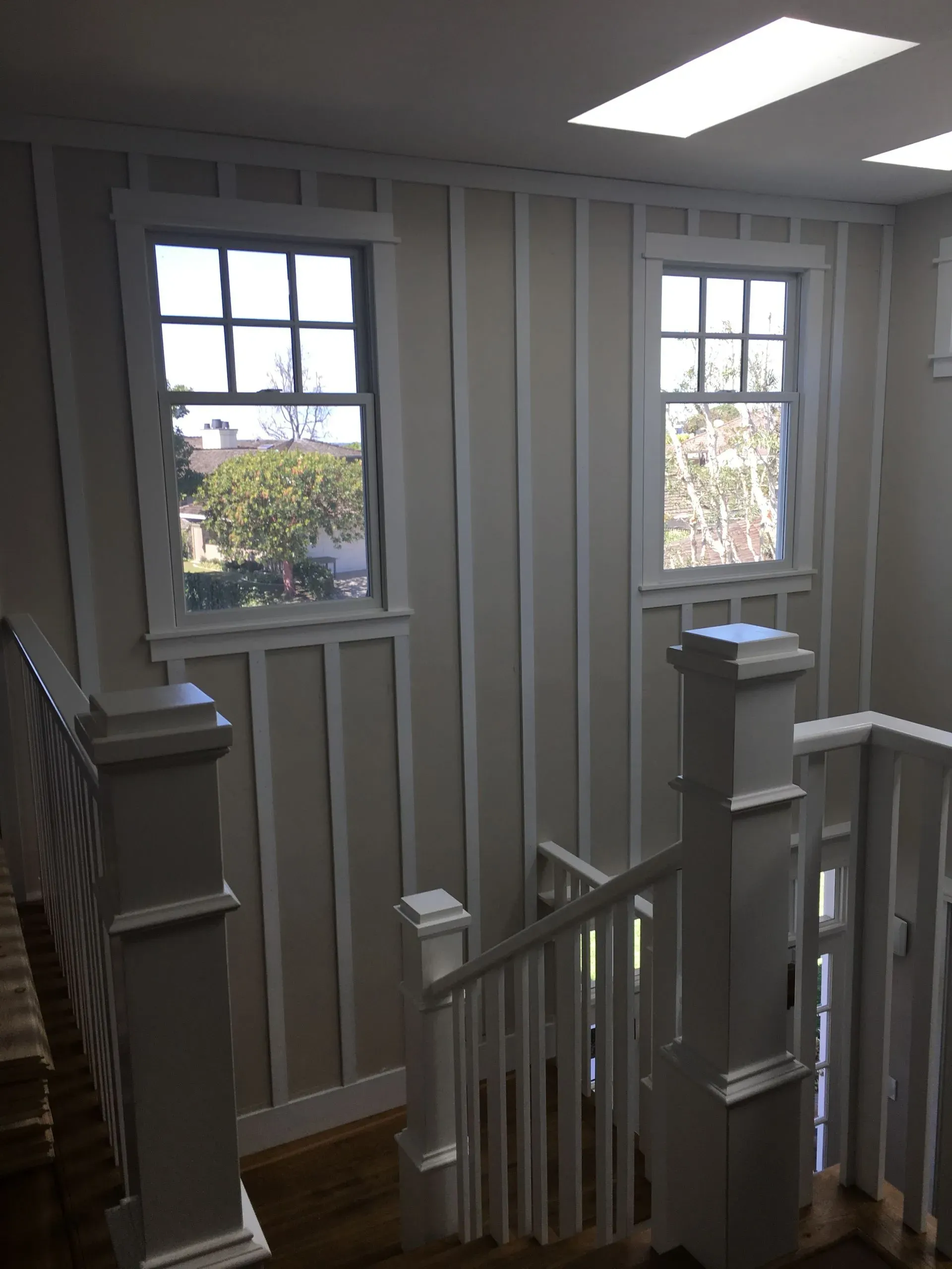 Upper-floor landing with white railings and two windows letting in daylight