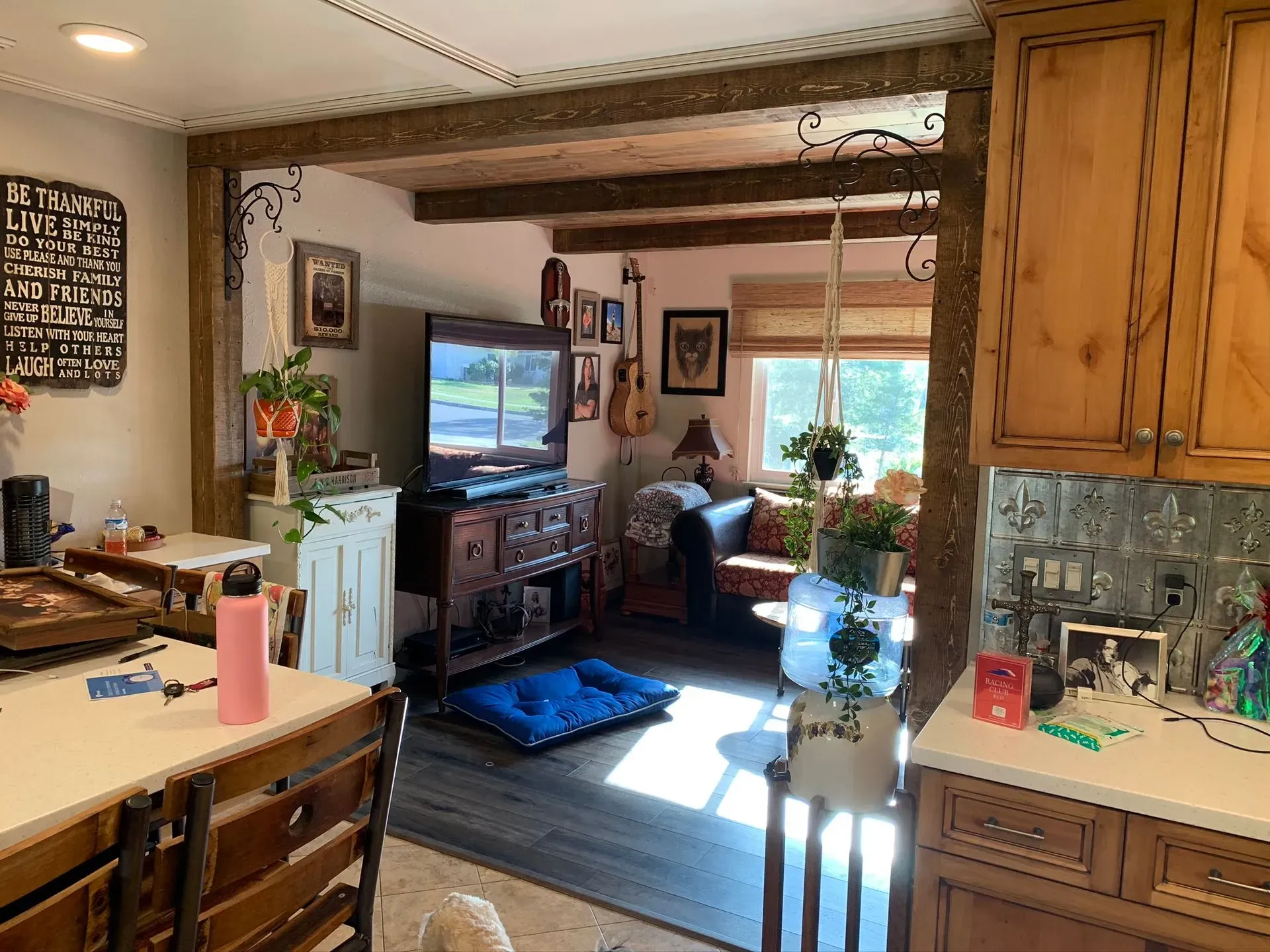 Cozy kitchen opening to a living room with TV, wooden cabinets, and a sunlit window