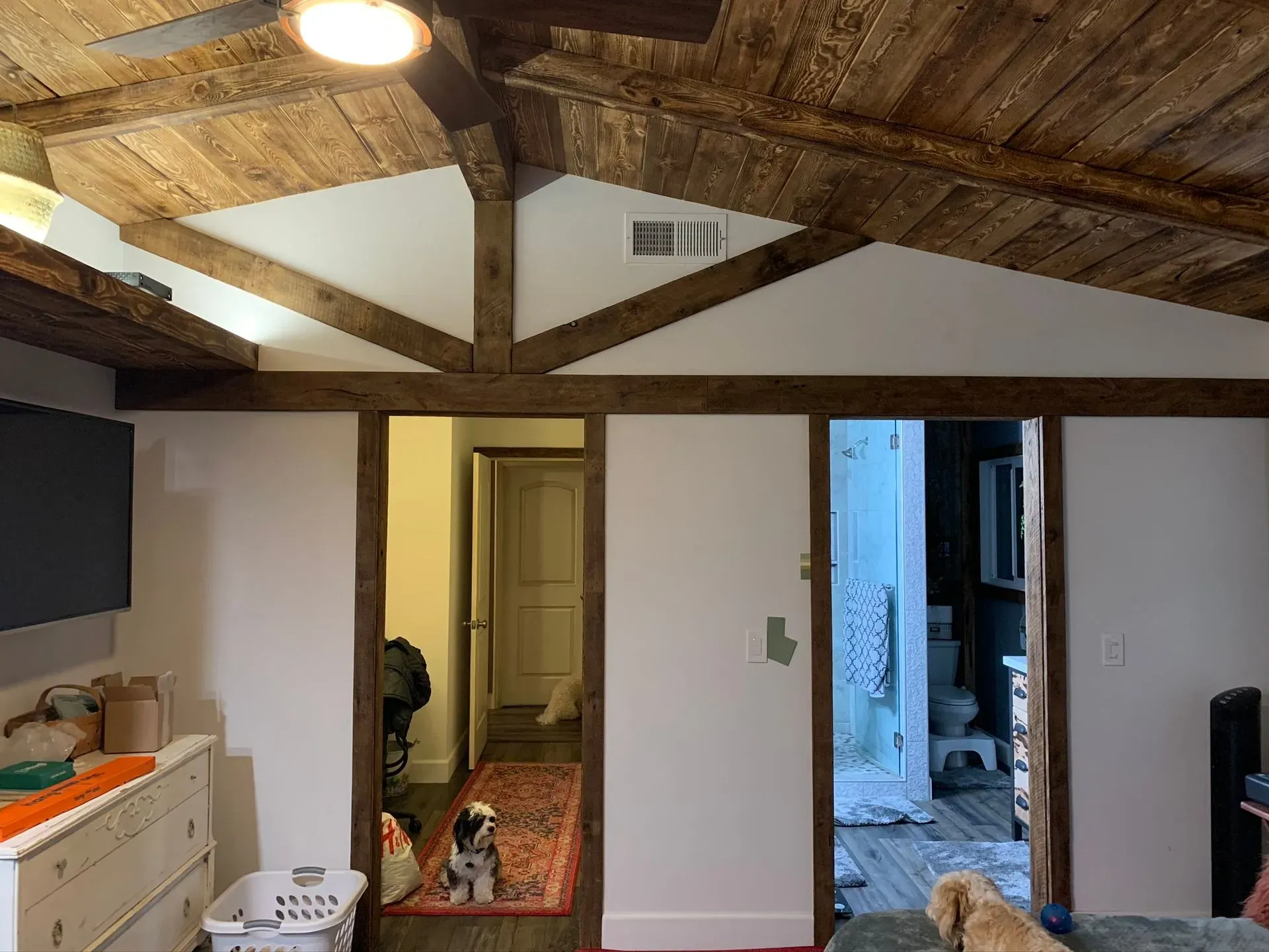 Rustic kitchen with exposed wood beams, white walls, and open doorways to a hallway and another room.