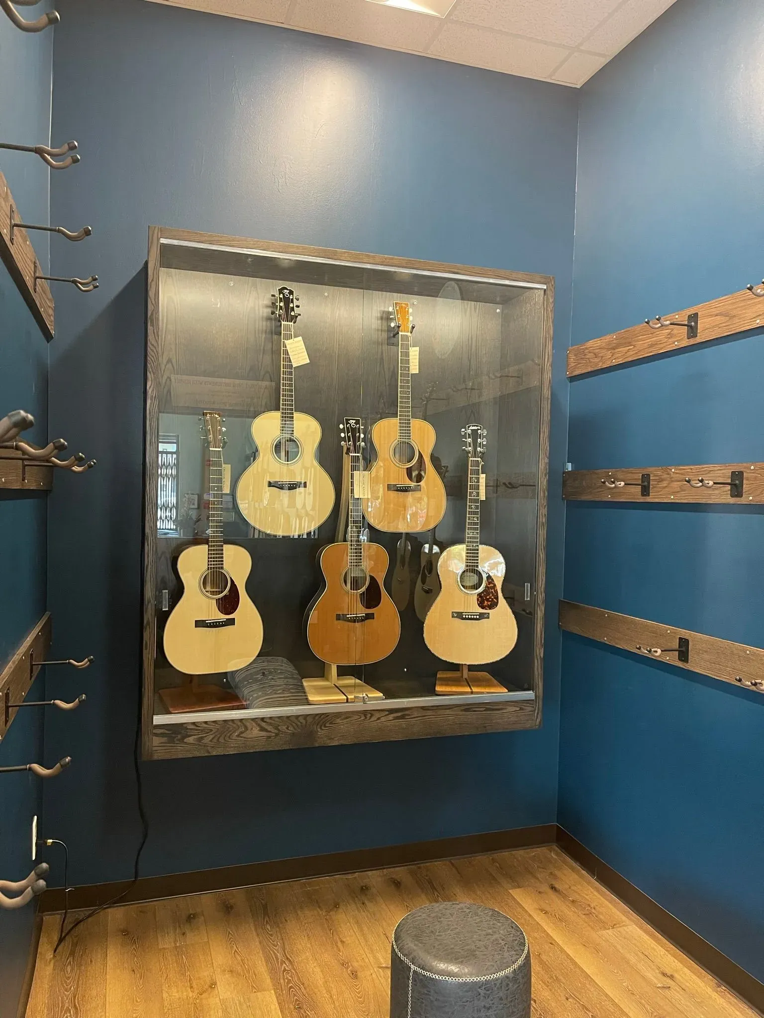Blue guitar showroom with several acoustic guitars in a glass display case