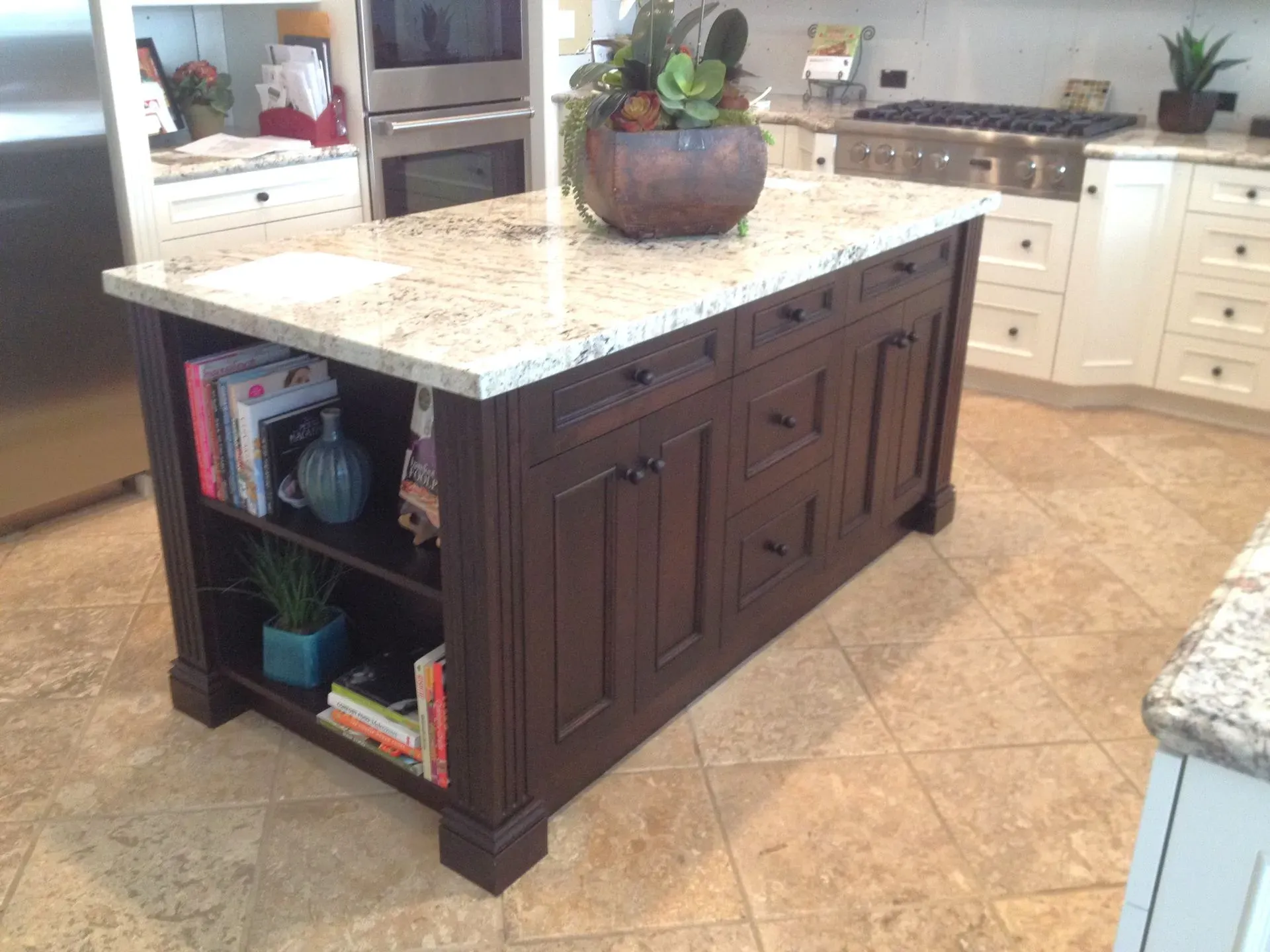Dark wood kitchen island with speckled granite countertop and open shelves in a bright kitchen