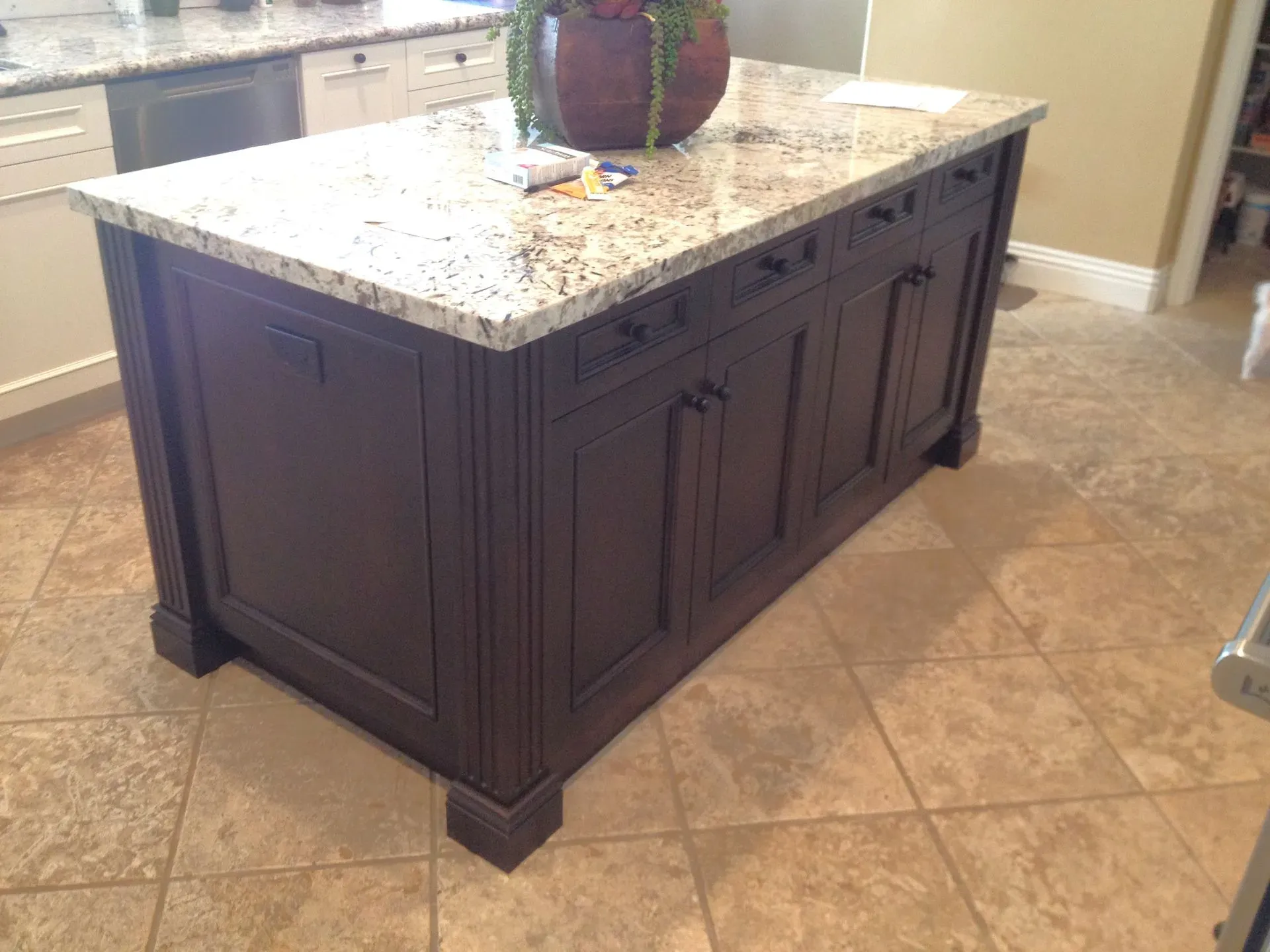 Kitchen island with dark wood cabinets and a light granite countertop on a tiled floor