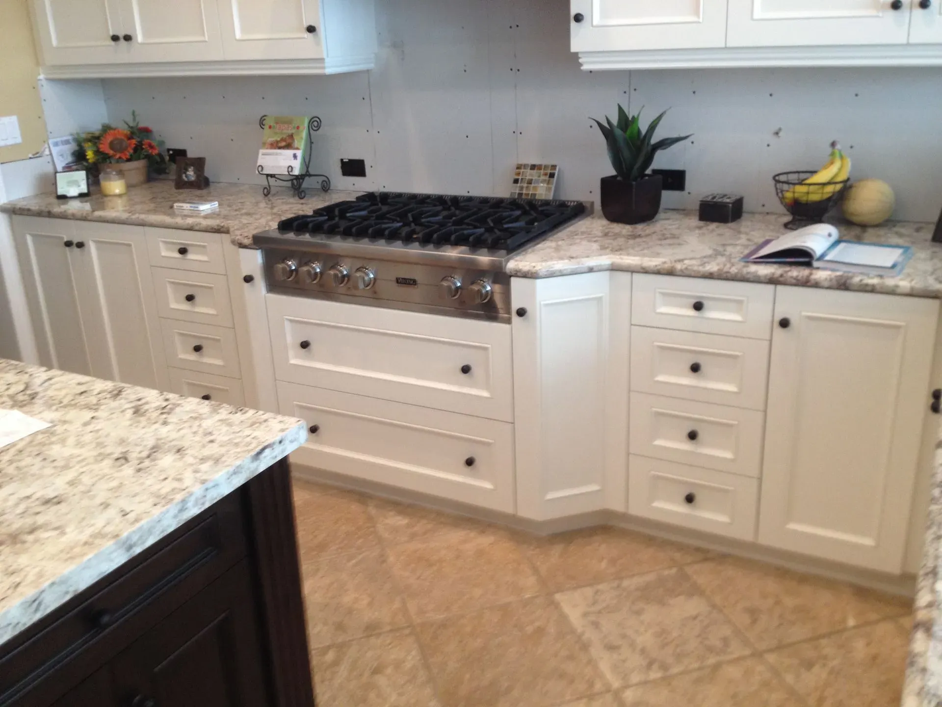 Bright kitchen with white cabinets, granite countertop, gas stove, and a potted plant on the counter