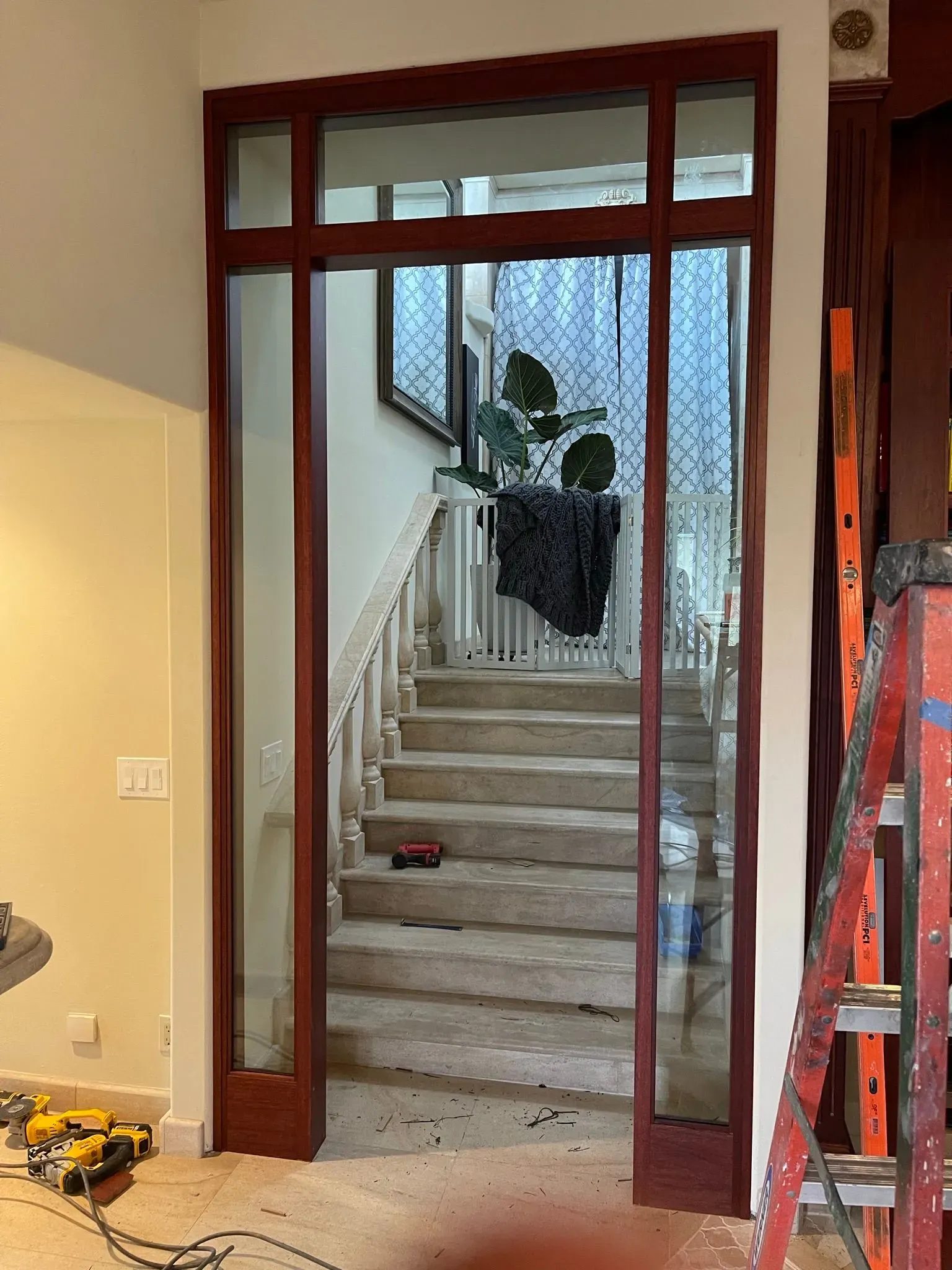 Interior doorway opening to a staircase with white railings and a large potted plant at the landing