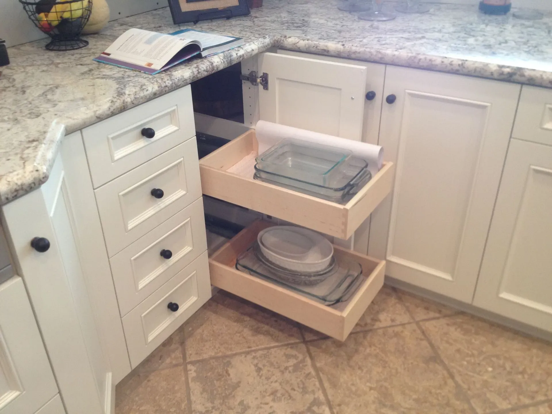 Kitchen corner with a white pull-out cabinet organizer holding trays and bowls
