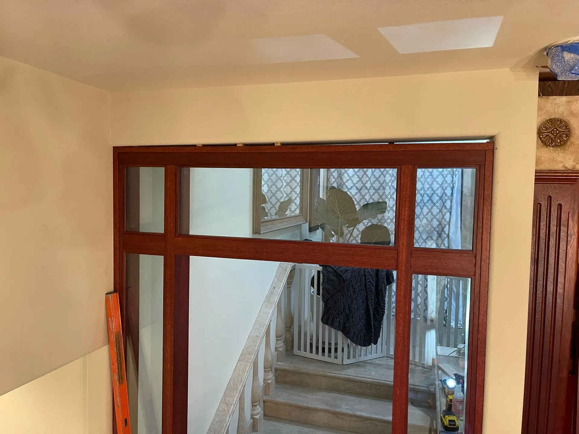 Interior view through a wooden-framed glass opening to a staircase and hallway beyond.